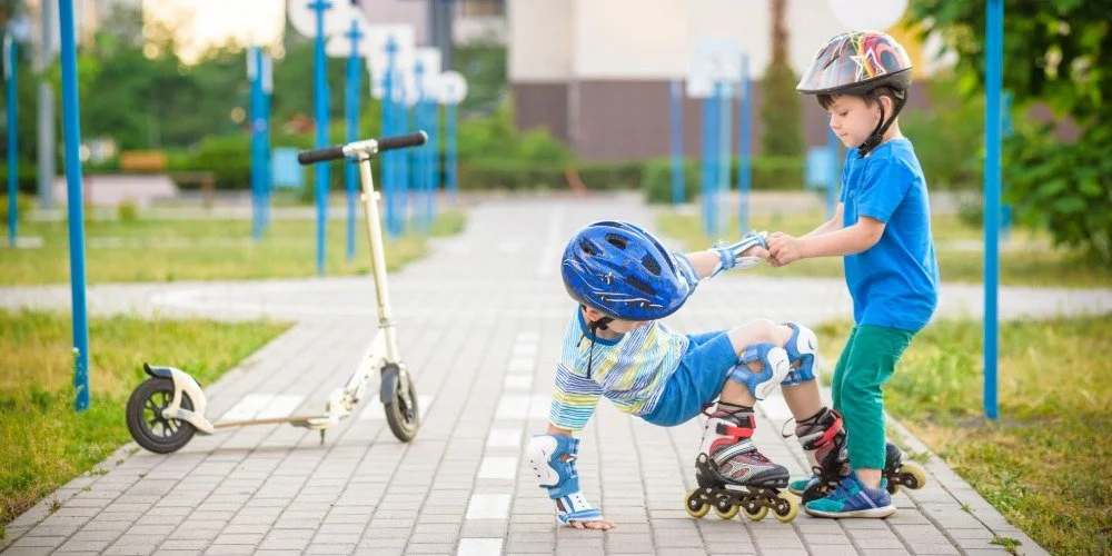 kid getting helped up from a fall from his friend