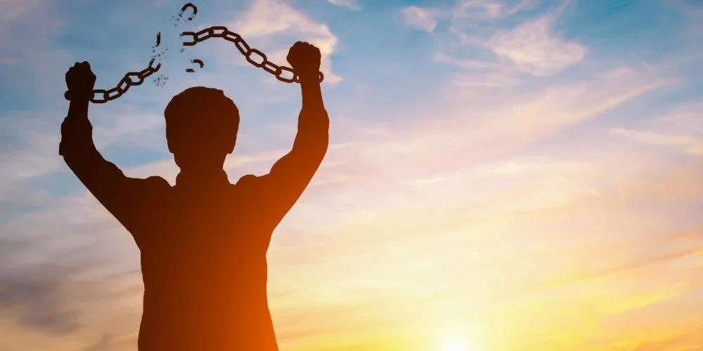 person lookin gout towards the sunrise and breaking their chains around their wrists