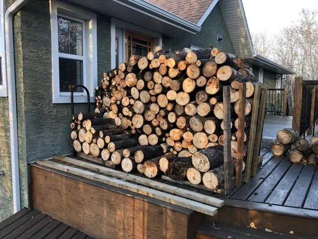 Neatly stacked pile of firewood on a wooden house deck.