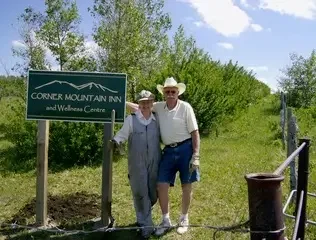 Founders standing beside the Corner Mountain and Wellness Centre sign, commemorating the establishment and growth of the property in a scenic rural setting.
