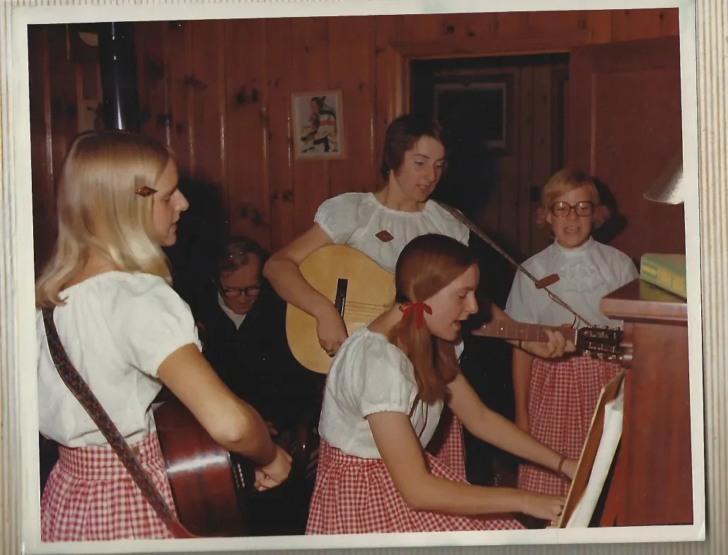Young musicians performing with guitars and piano in traditional attire during a community music gathering at the inn.