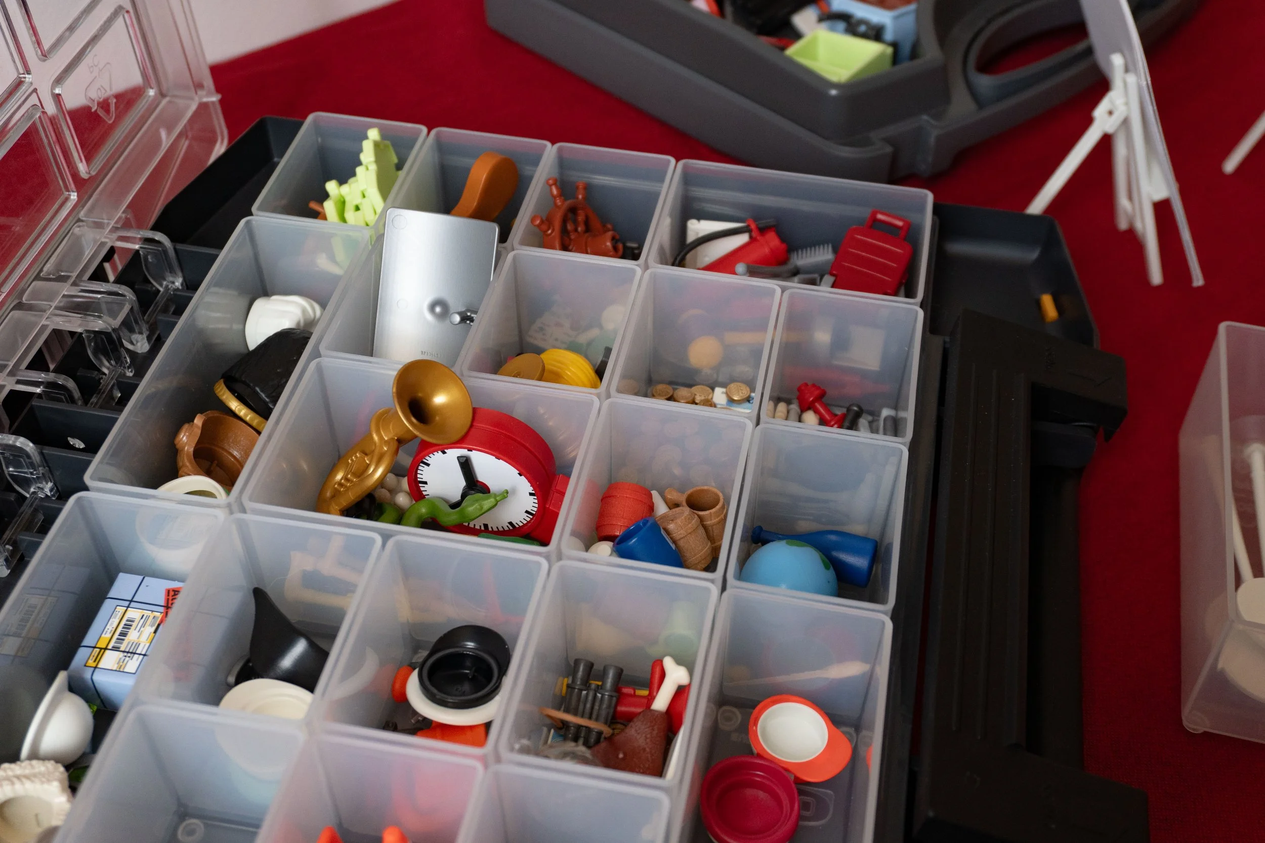 Close up shot of a box of Pro.Play method elements laid out for a workshop. Bright coloured miniature objects are nestled in each of the small boxes.