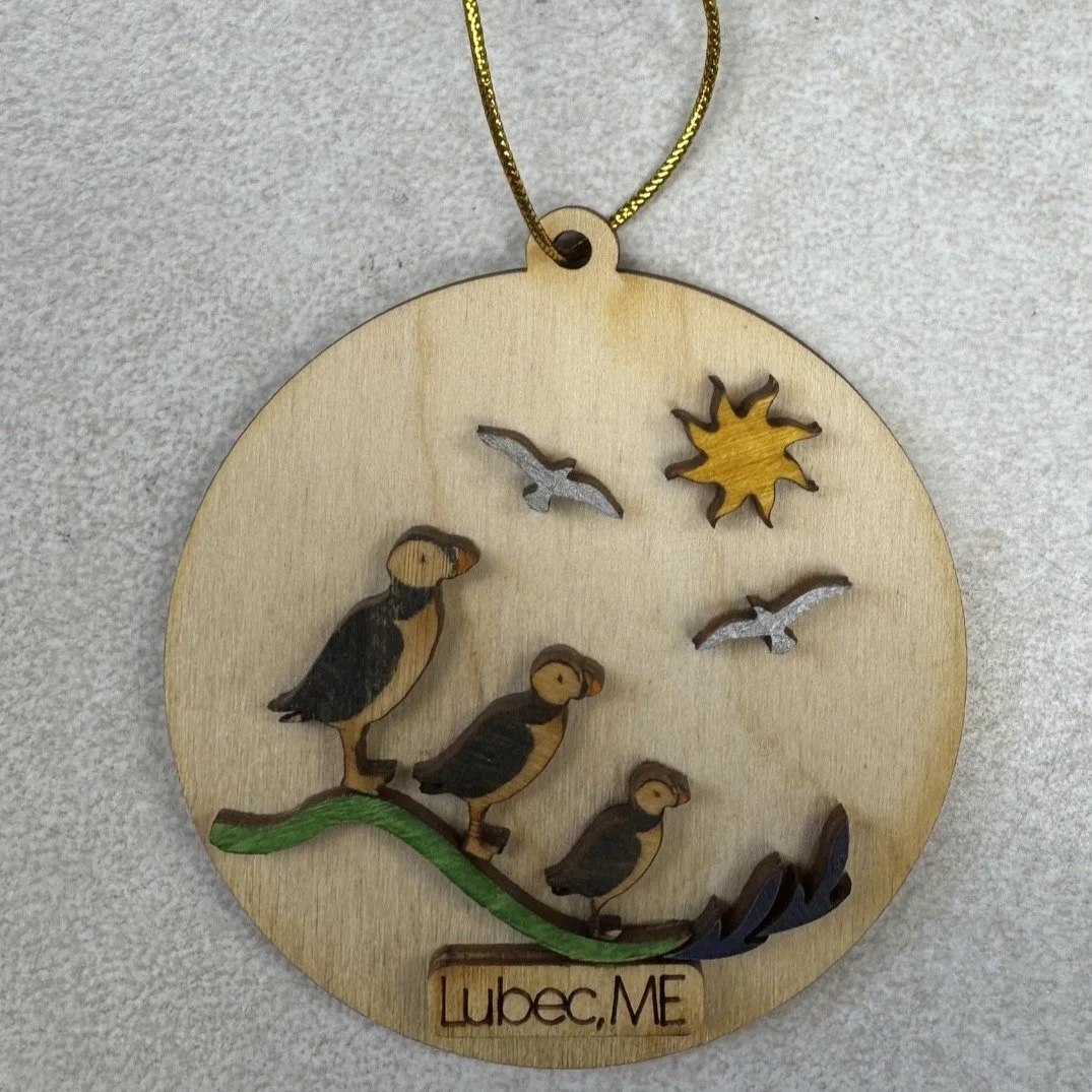 Souvenir wooden ornament with puffins, a sun, and a sign reading "Lubec, ME."