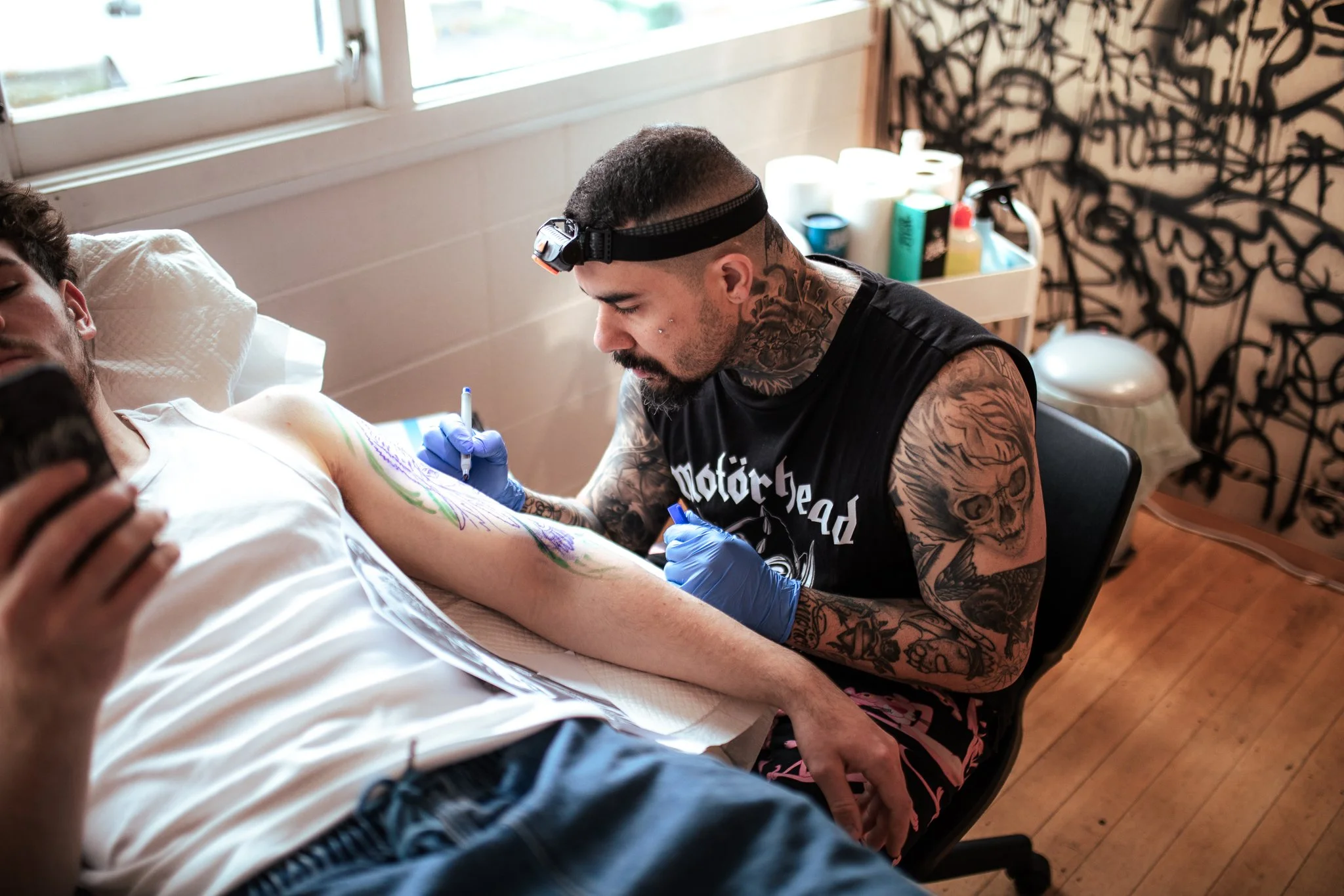 Tattoo artist working on a client's arm in a tattoo studio.