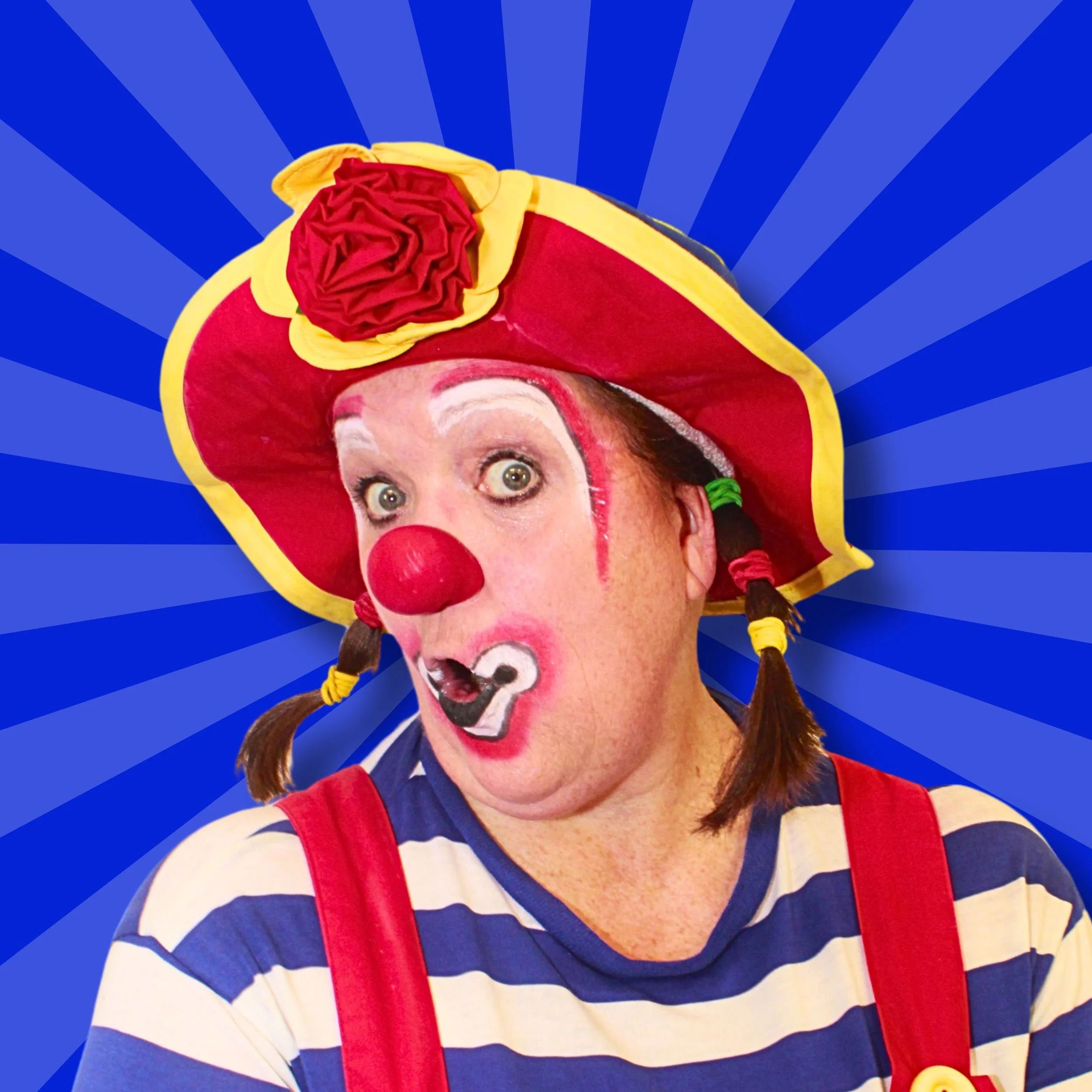 A clown wearing a red hat, pigtails, and a blue-striped shirt