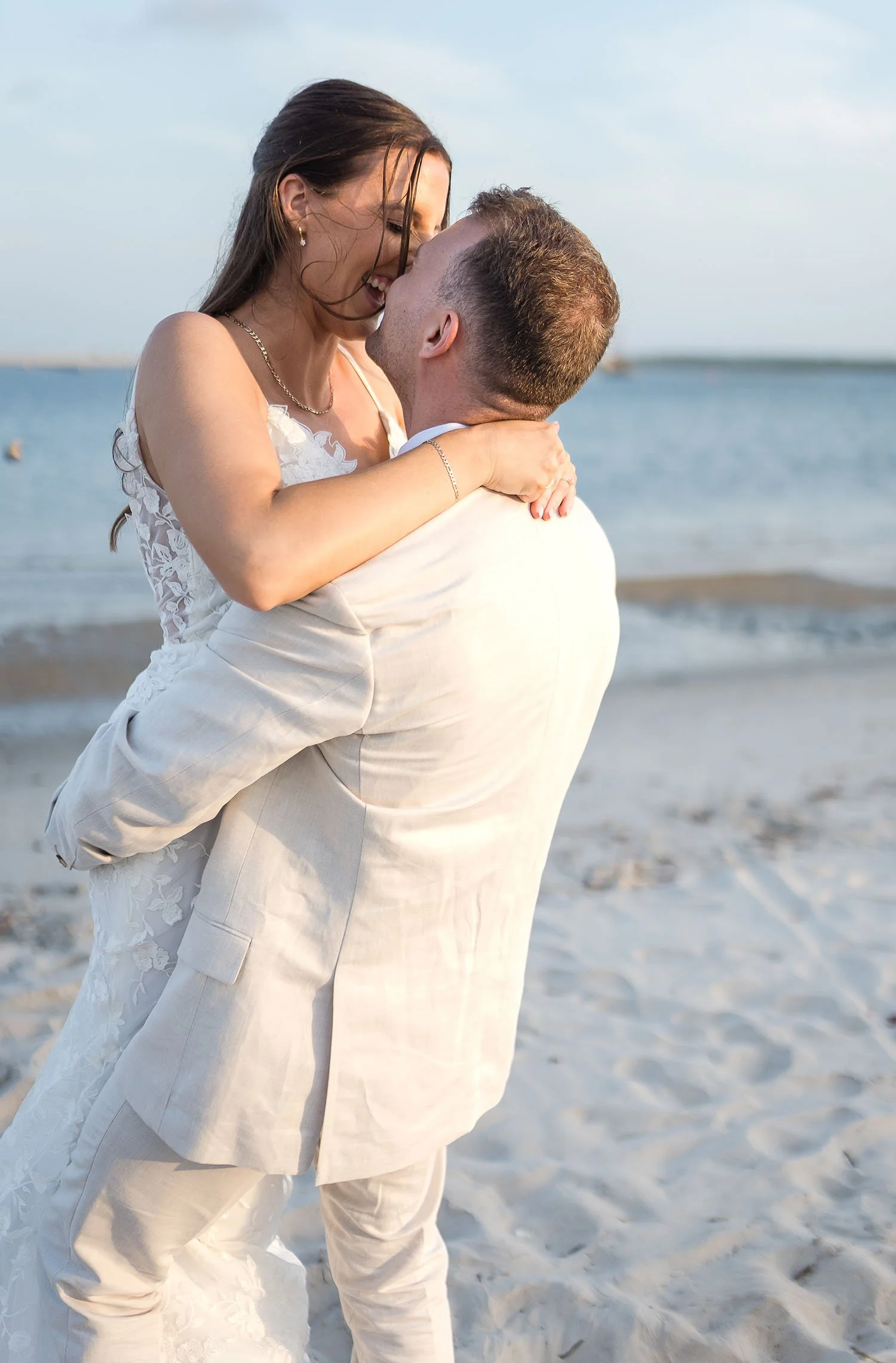 candid moment of groom lifting bride on the beach