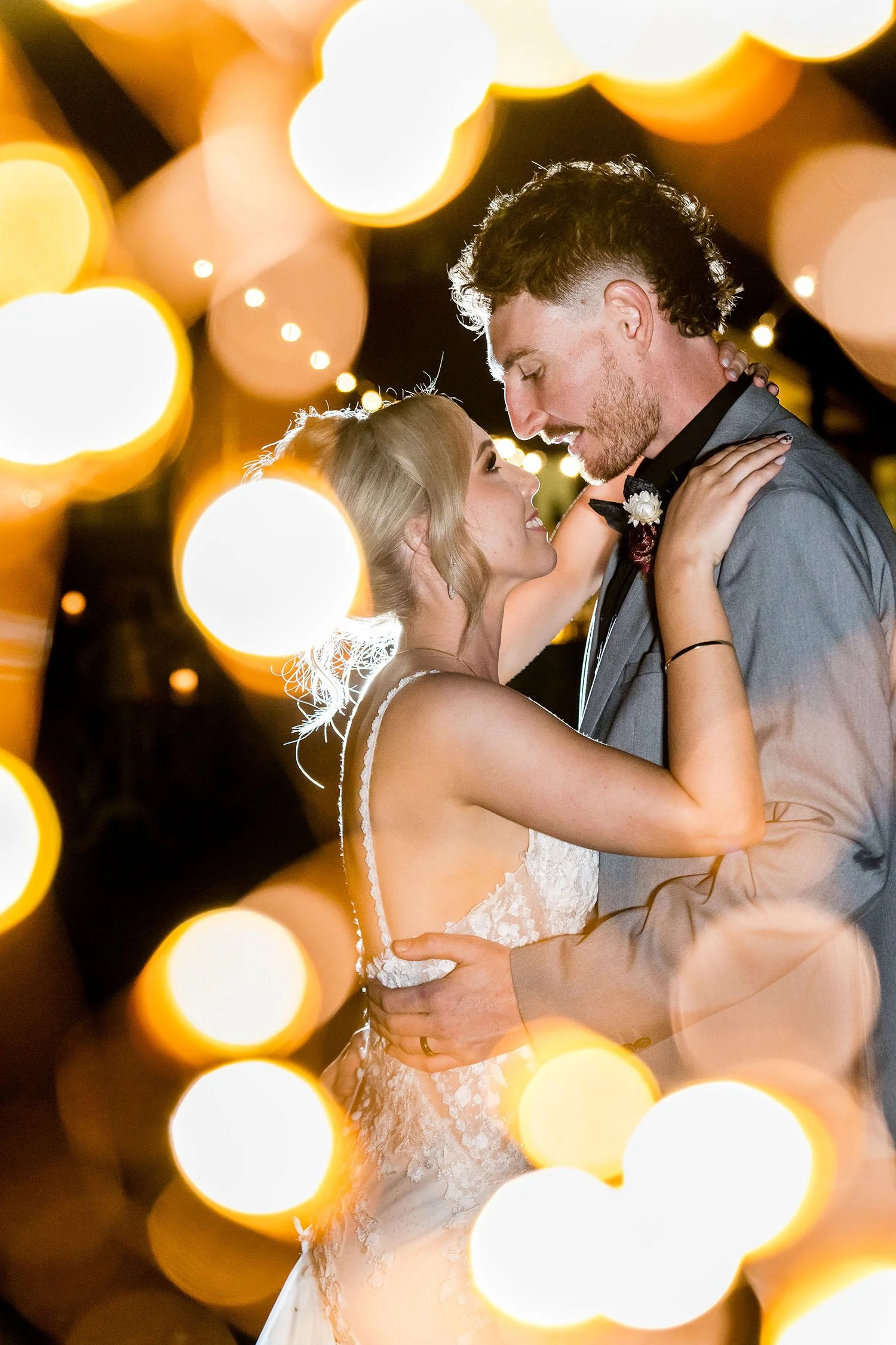 bride and groom under fairy lights at night time