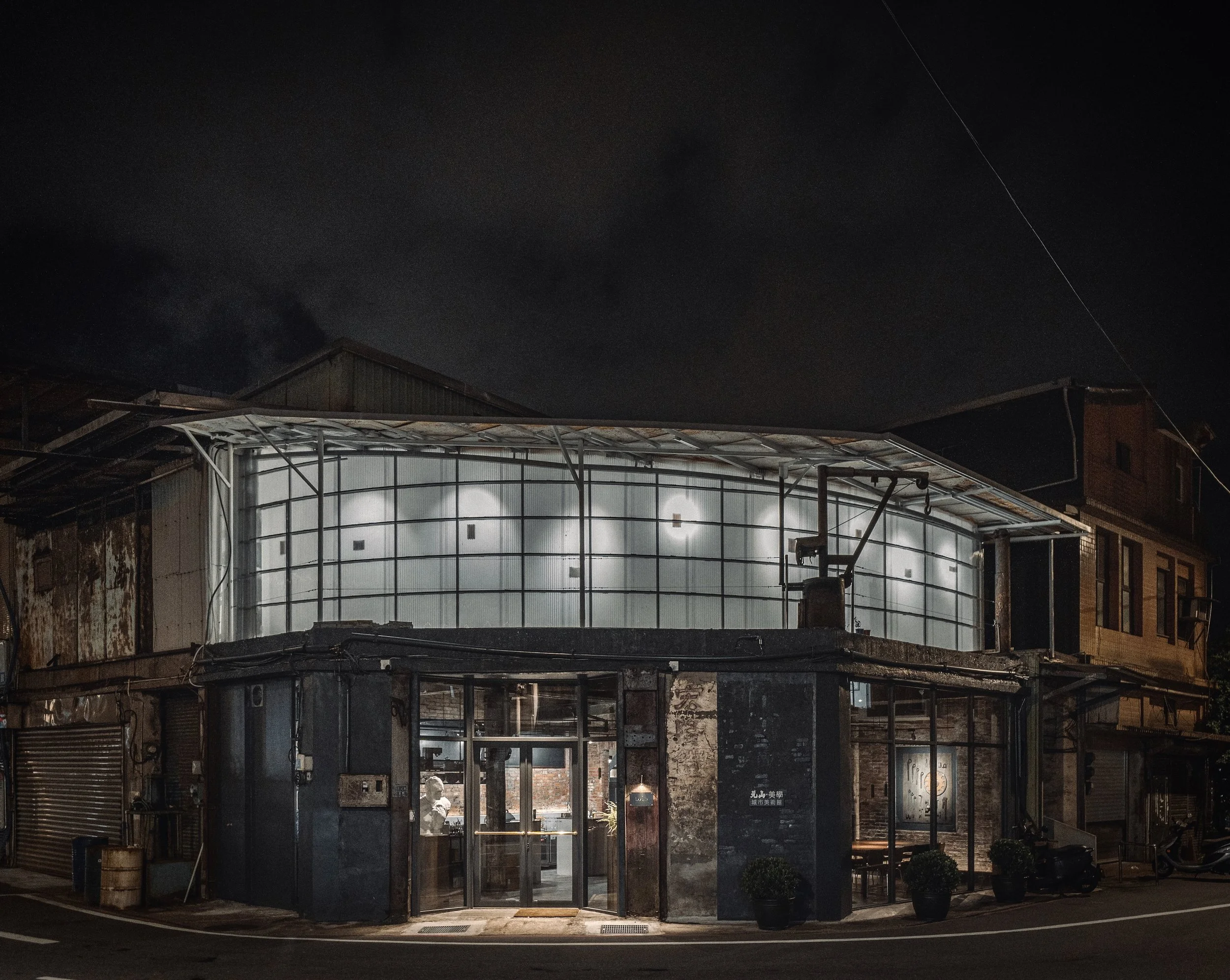      

 
   元山・美學城市美術館-正濱館     一泓弧線在轉角生成，抹去邊界的尖銳，柔順滑入城市的海濱一隅。  這筆觸是從歷史劃入現代的光，將歷史的肌理照亮，輪廓出新的面貌。  讓重量停留在下層，記憶得以沉澱；  透光的形體在上方漂浮，化為一盞城市美學燈箱。     這座建築誕生於城市的正濱漁港的邊角，日據時代起建，一開始僅為結構簡單的庇護所，後來也曾在基隆成為魚港重鎮之際，化身為維修漁船輪機的重機械工廠。團隊一開始造訪此基地，已是廢墟，一樓是五邊形的平面，二樓則在時間中自行生長出