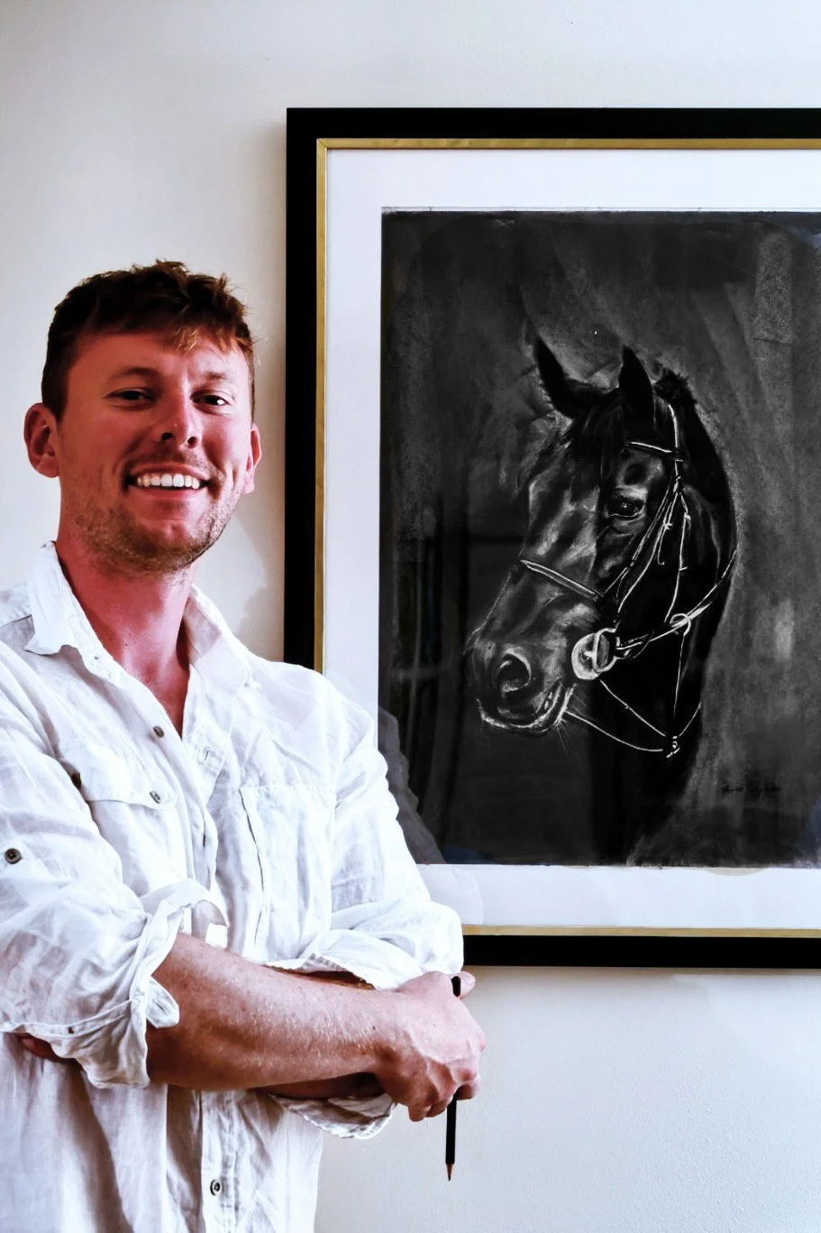Tom standing beside his framed charcoal drawing of a horse