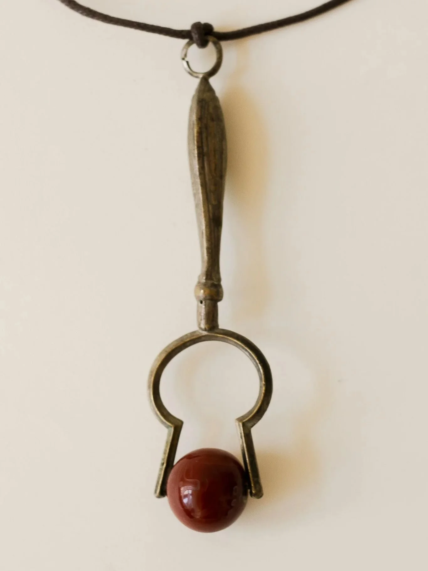 An early 19th century embossed brass and carnelian facial roller with a suspension loop to hang from a cord or chain and wear as a pendant.

Supplied on a brown leather cord.

Height: 12.5cm
