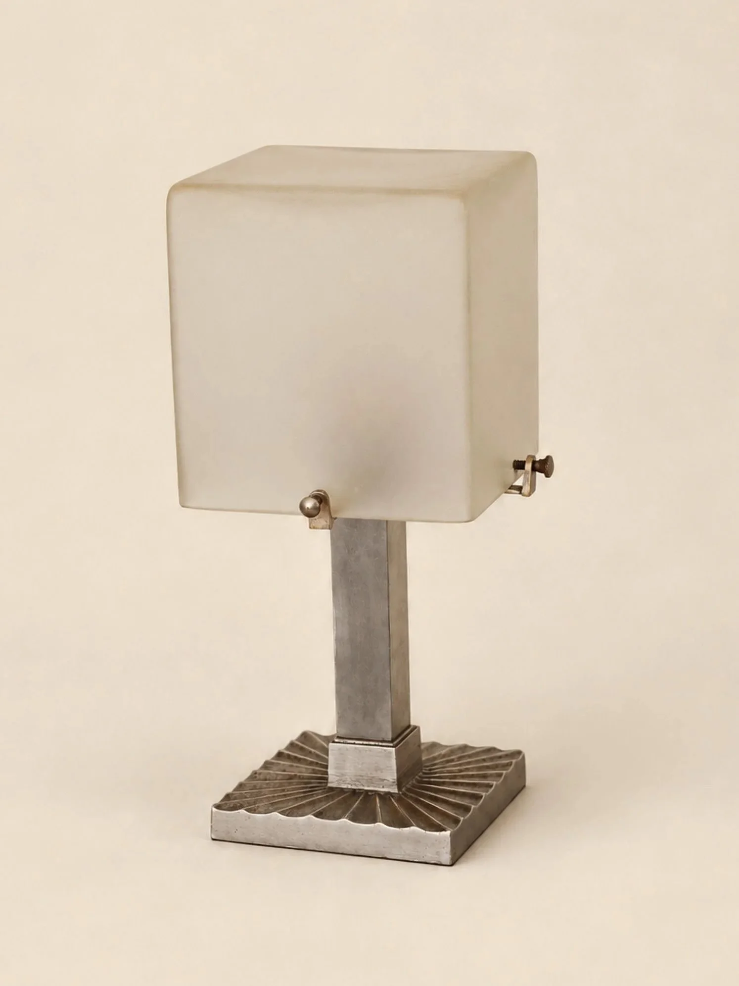 A modernist silver nickel plated bronze table lamp featuring a vertical column stem, square base with radiating fluted pattern and a cubic frosted glass shade. 

French, C1930.

Height: 26cm
Shade diameter: 12cm
Base diameter: 10cm