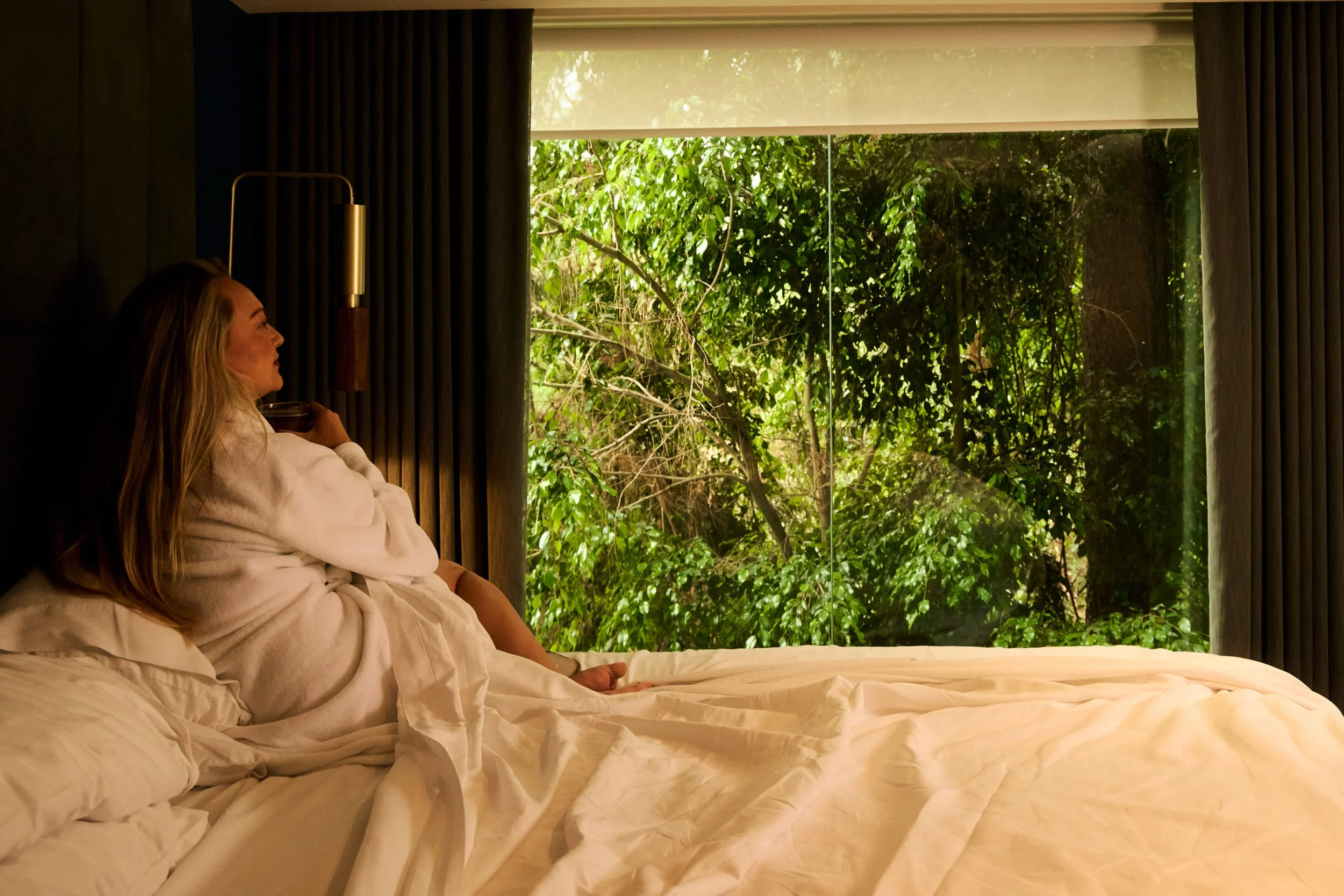 Woman laying on hotel bed with robe
