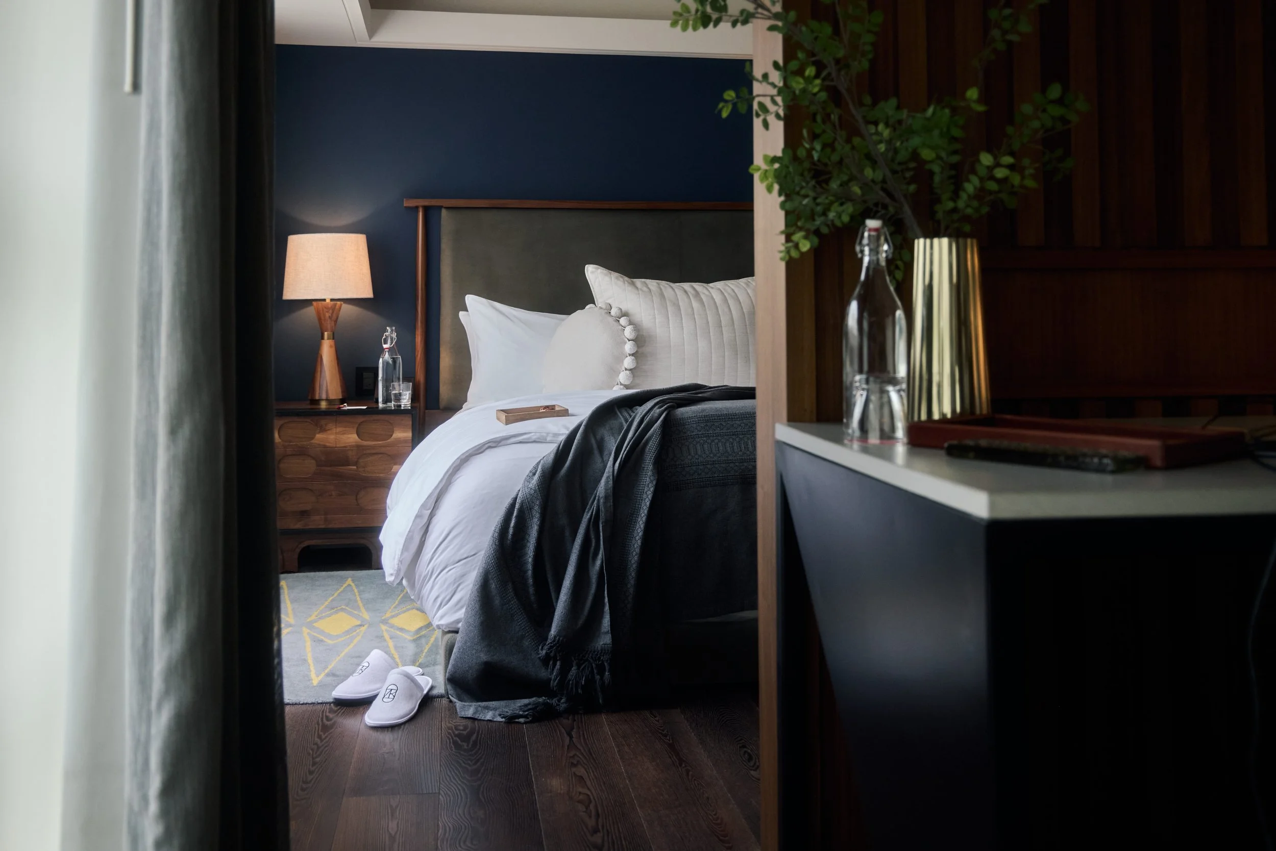 Hotel bedroom with lush decor, a large bed with white linens and complimentary slippers