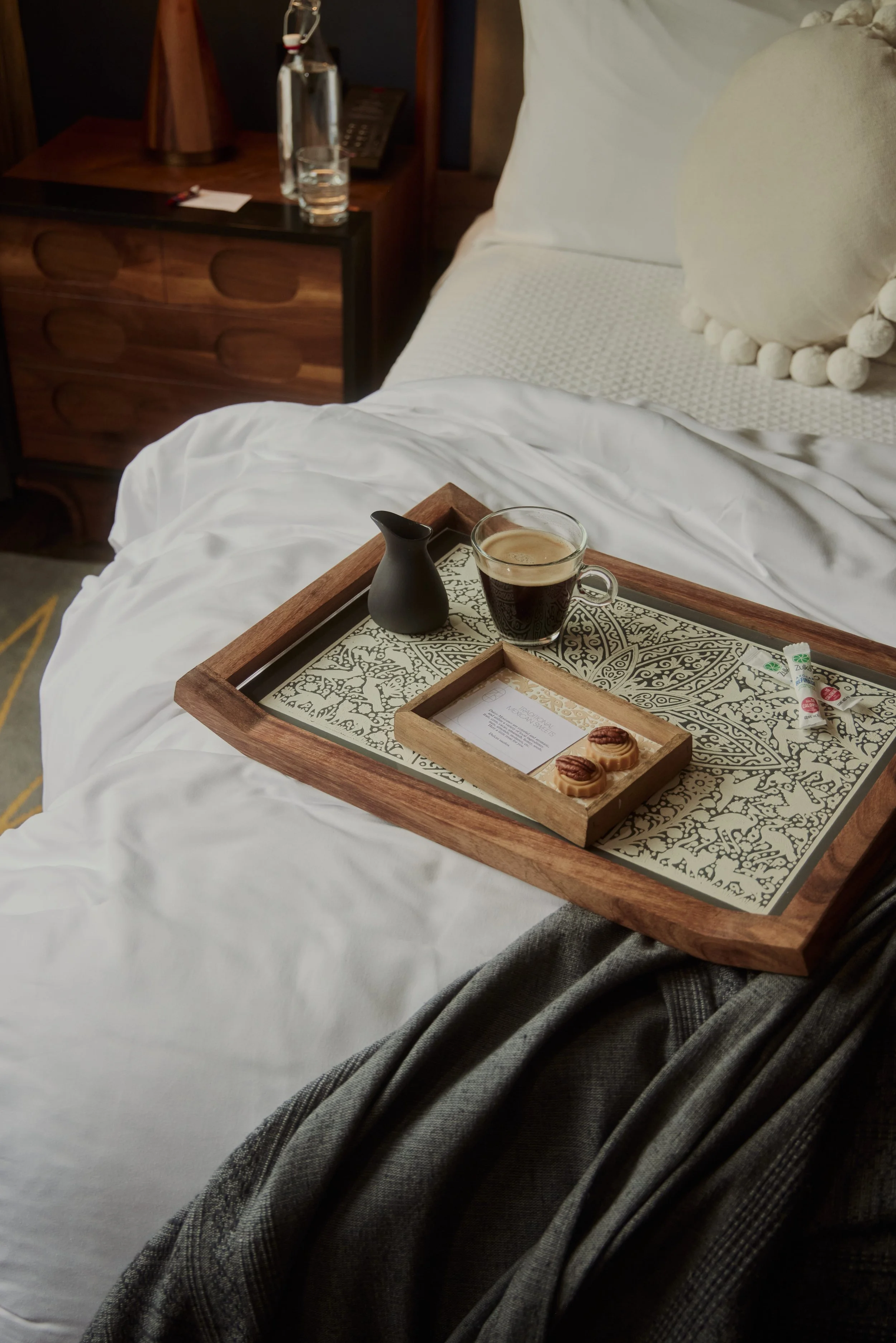 Tray with coffee placed on top of hotel room bed