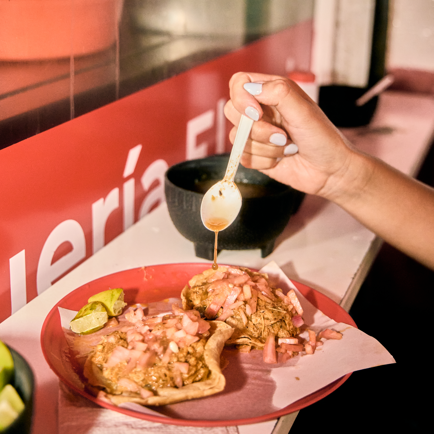 Fresh birria tacos with onions and lime wedges, finished with sauce at a Mexico City restaurant.