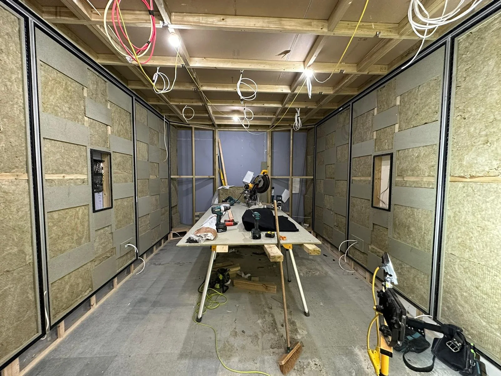 Works in progress in the Dolby Atmos studio at Wired Masters, London, showing timber framing, acoustic treatment build-up and in-wall speaker openings.