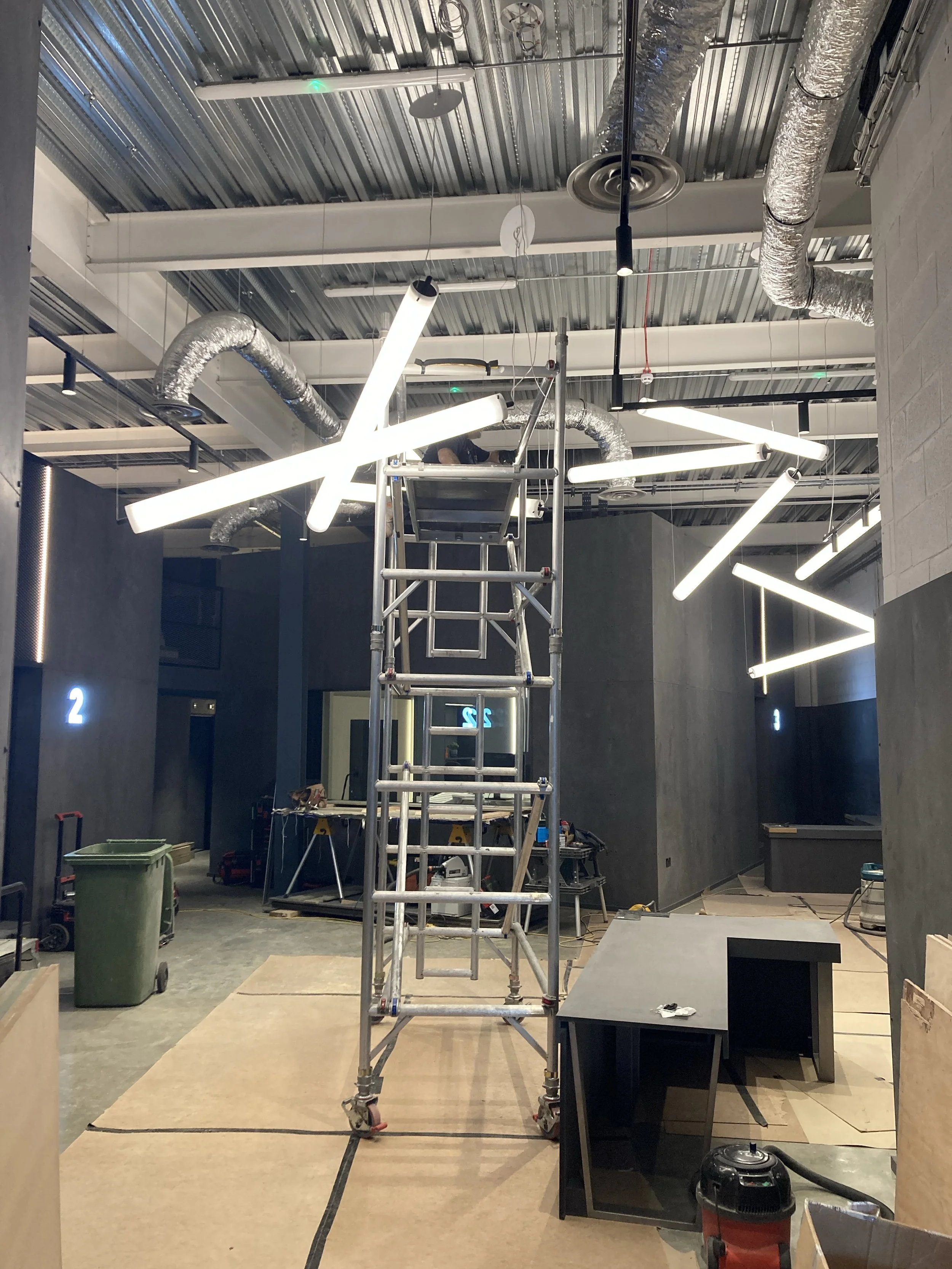 Works in progress in the reception area at Wired Masters, London, showing installation of Pistillo pendant lights with a scaffold tower.