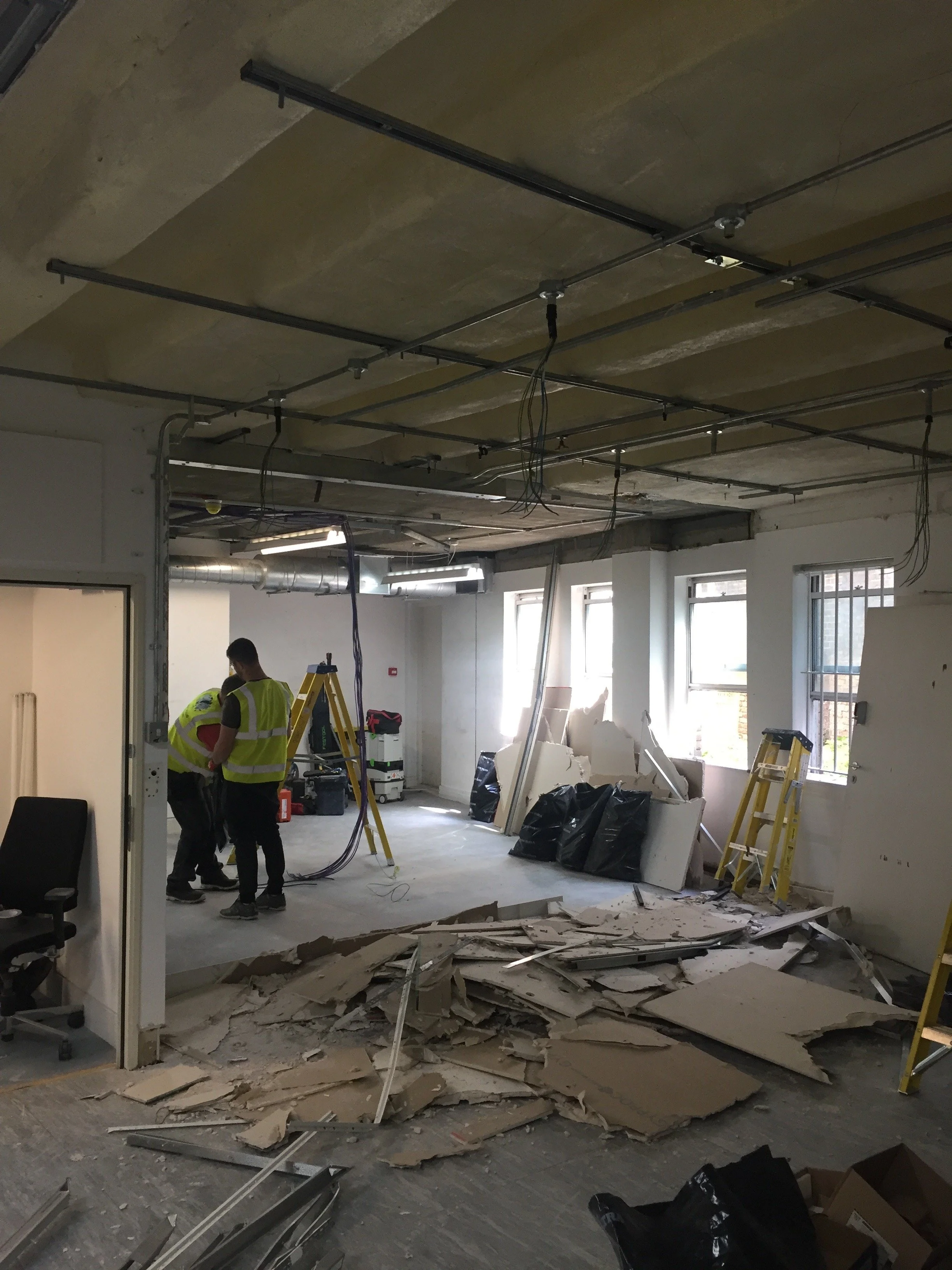 Strip-out works in progress, wide view of the space showing exposed structure and cleared floor area.