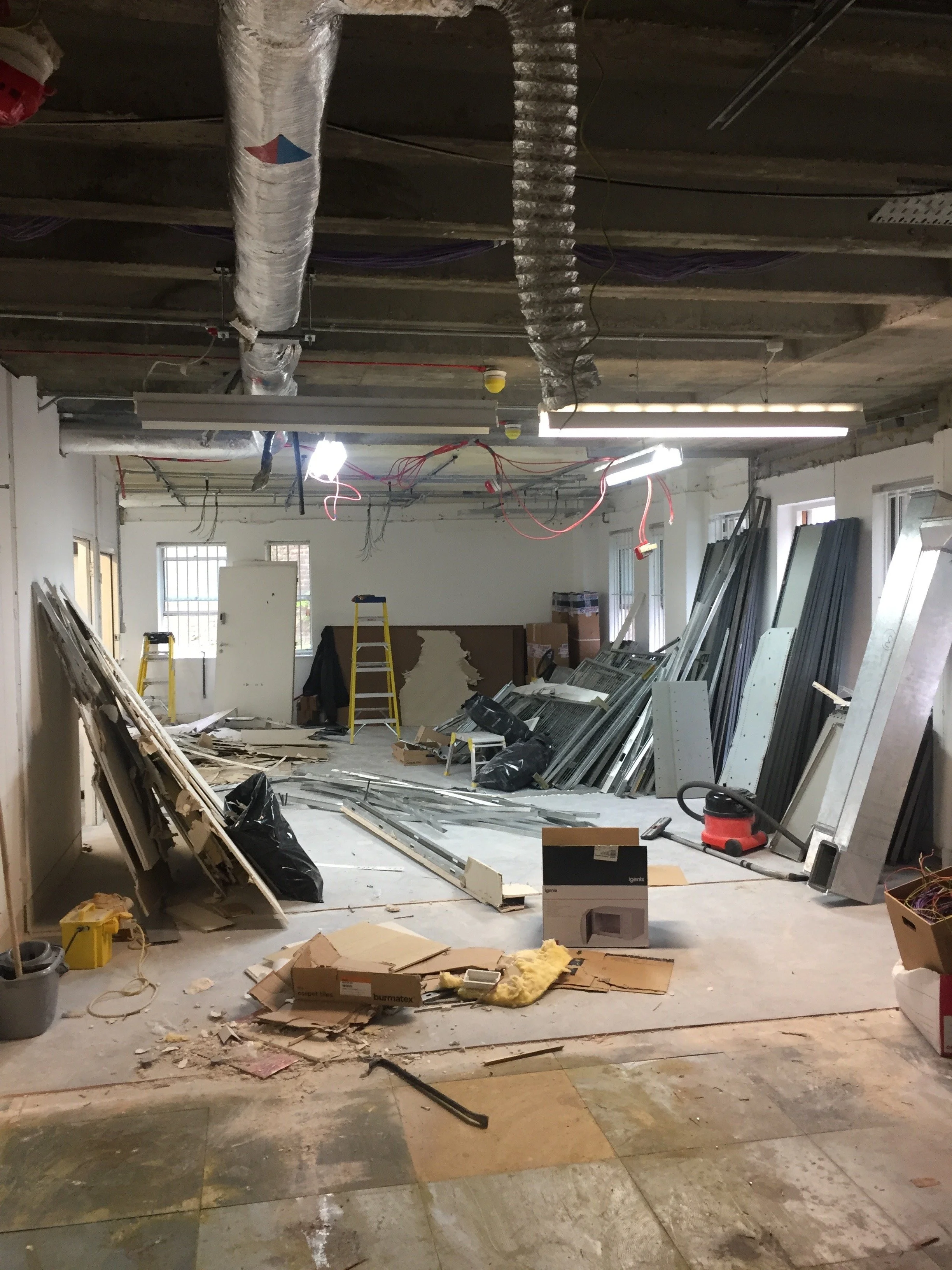 Strip-out works in progress, view from the opposite end showing exposed services and partition removals.