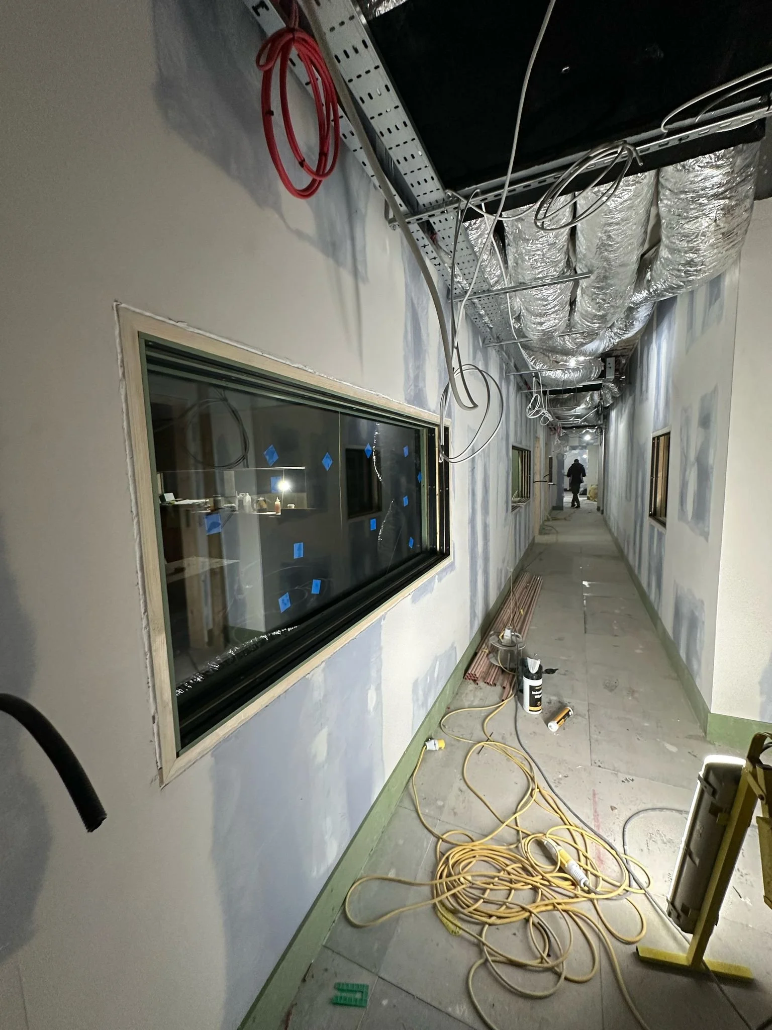 Sound lock corridor under construction at Global, Four Millbank, showing flexible ductwork and acoustic glazing.