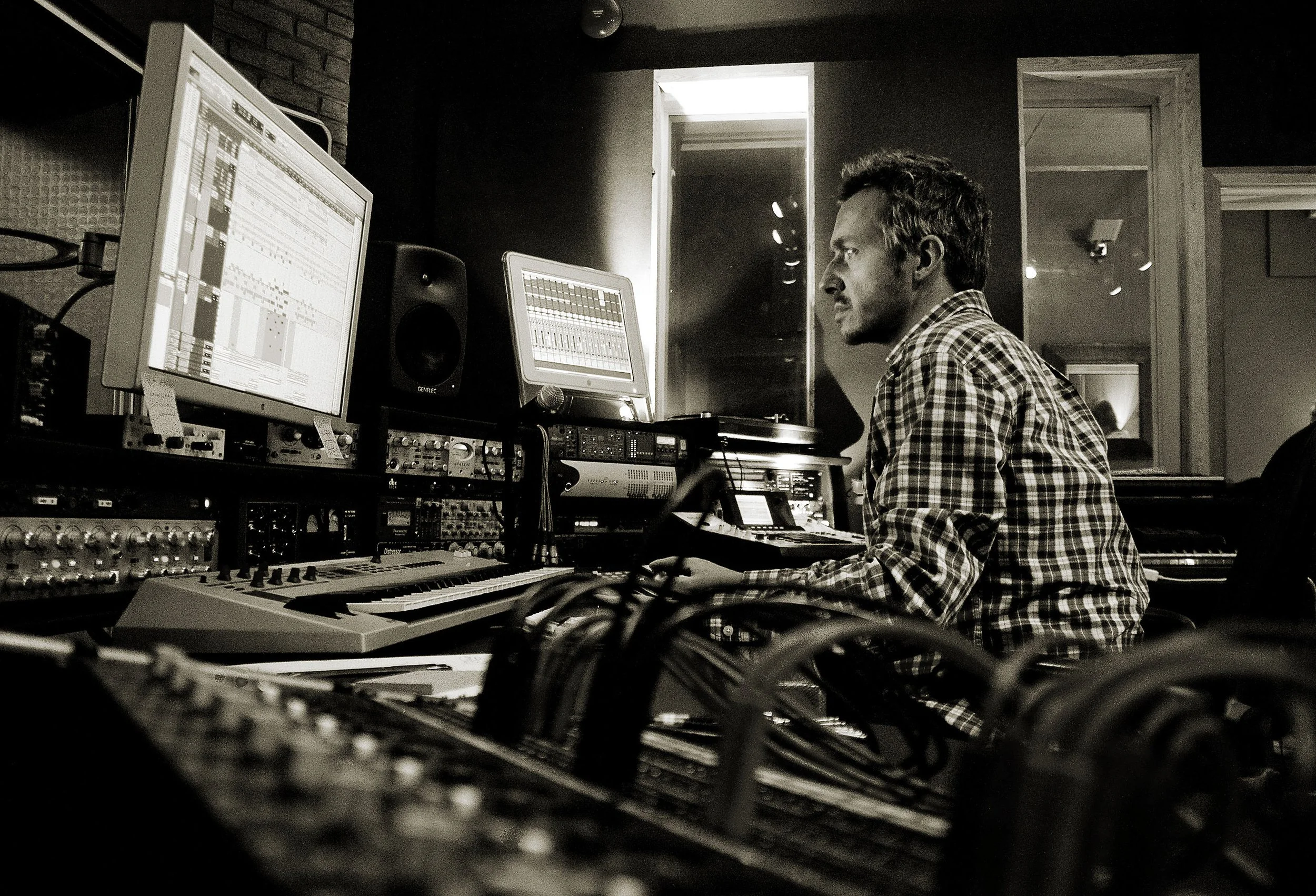 Black and white portrait of producer Fraser T Smith at the mix desk in his control room, editing in Pro Tools.