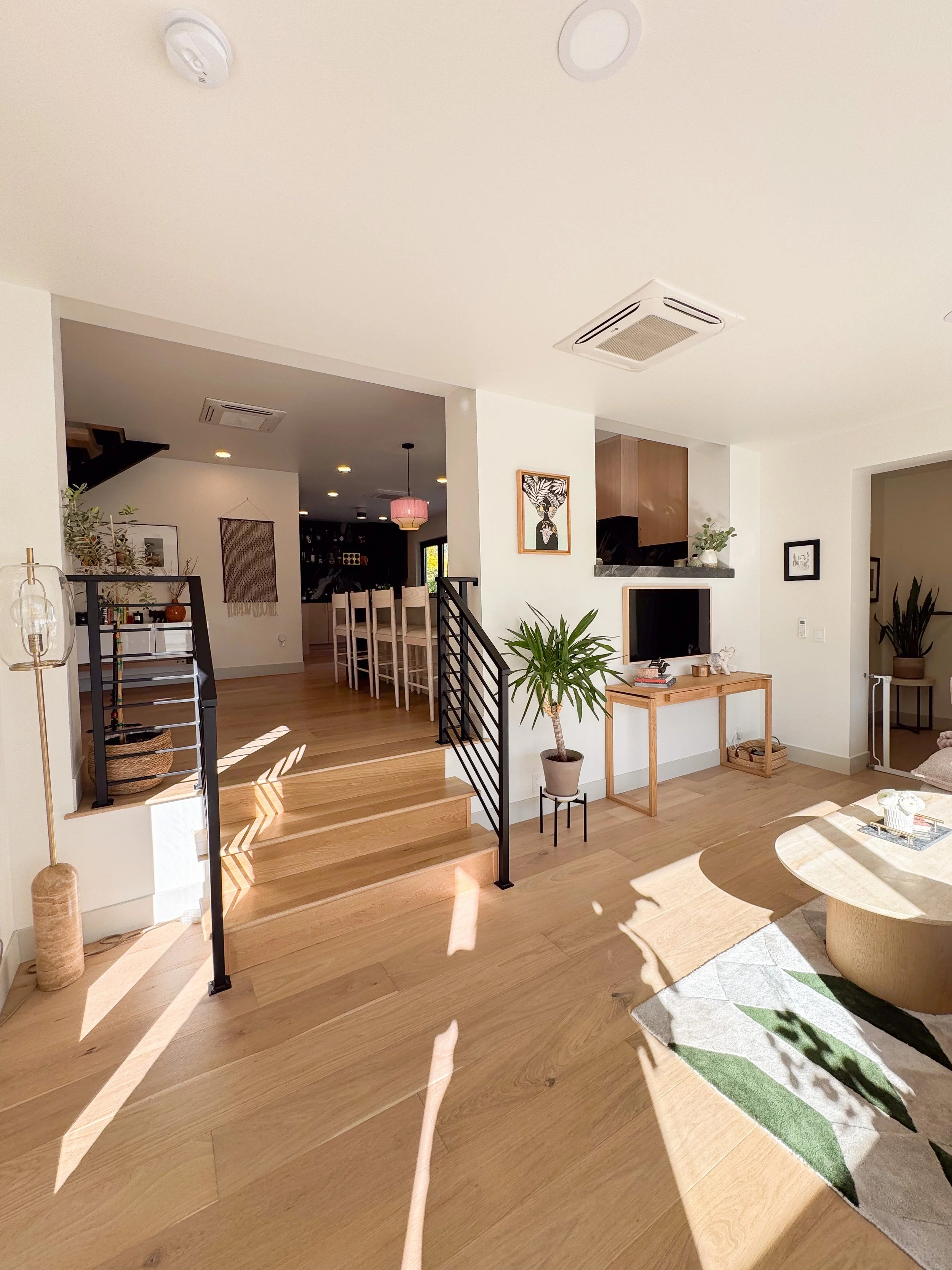 Open-concept living area in a Denver pop-top renovation featuring custom stair detailing, hardwood floors, and integrated indoor-outdoor light