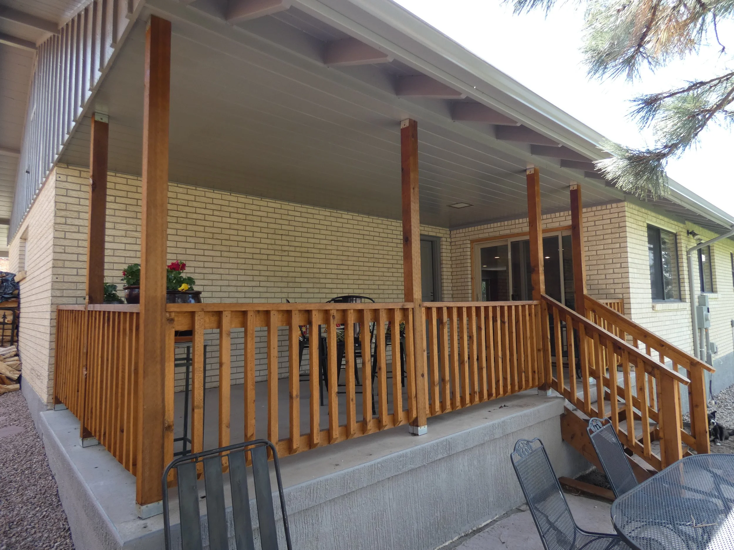 Completed covered front porch on a Denver home renovation, featuring wood posts, railing, and a shaded outdoor seating area built by Prenvalley Builders.