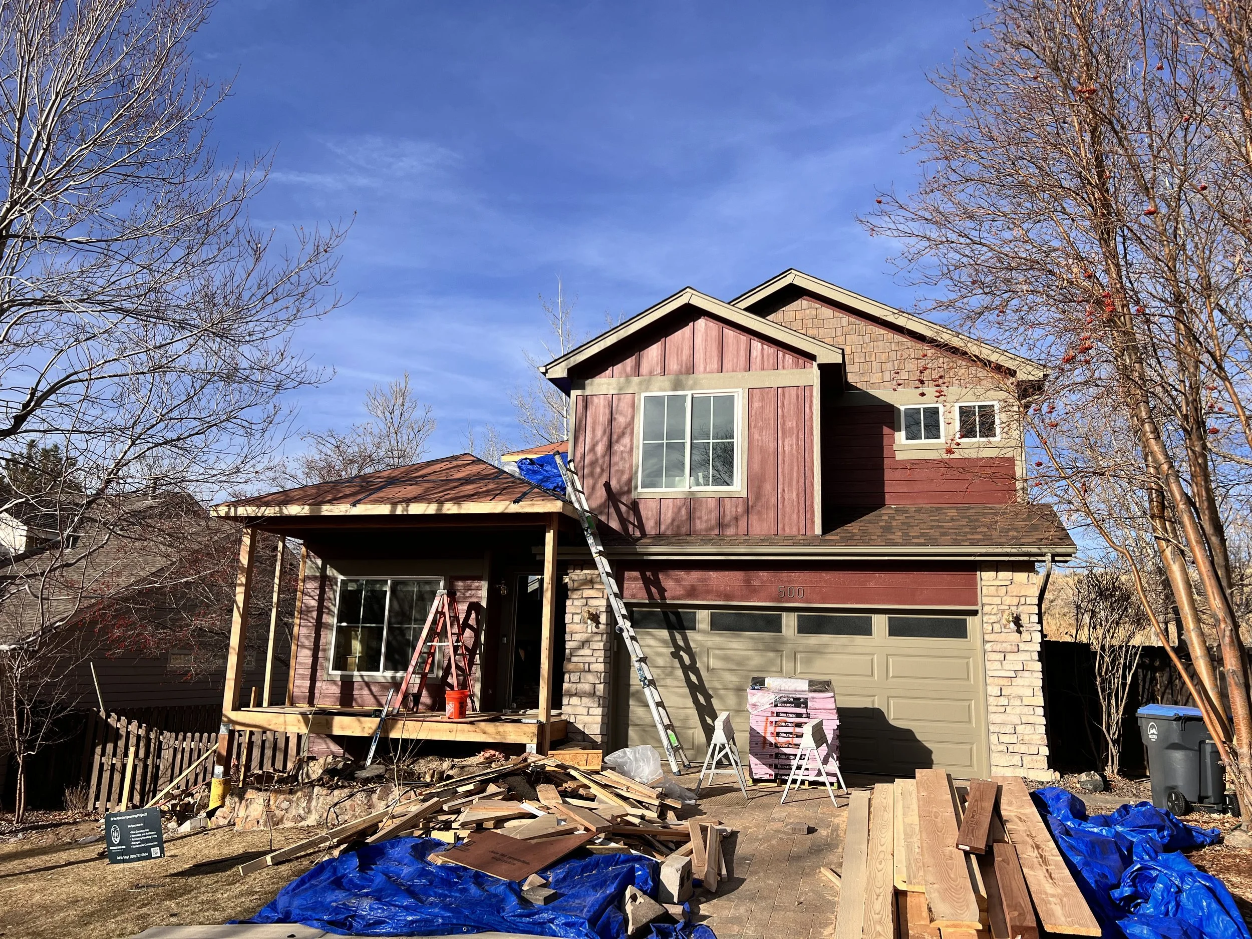 Exterior construction in progress on a pop-top renovation in Golden, Colorado, showing a partial second-story addition and new front porch framing.