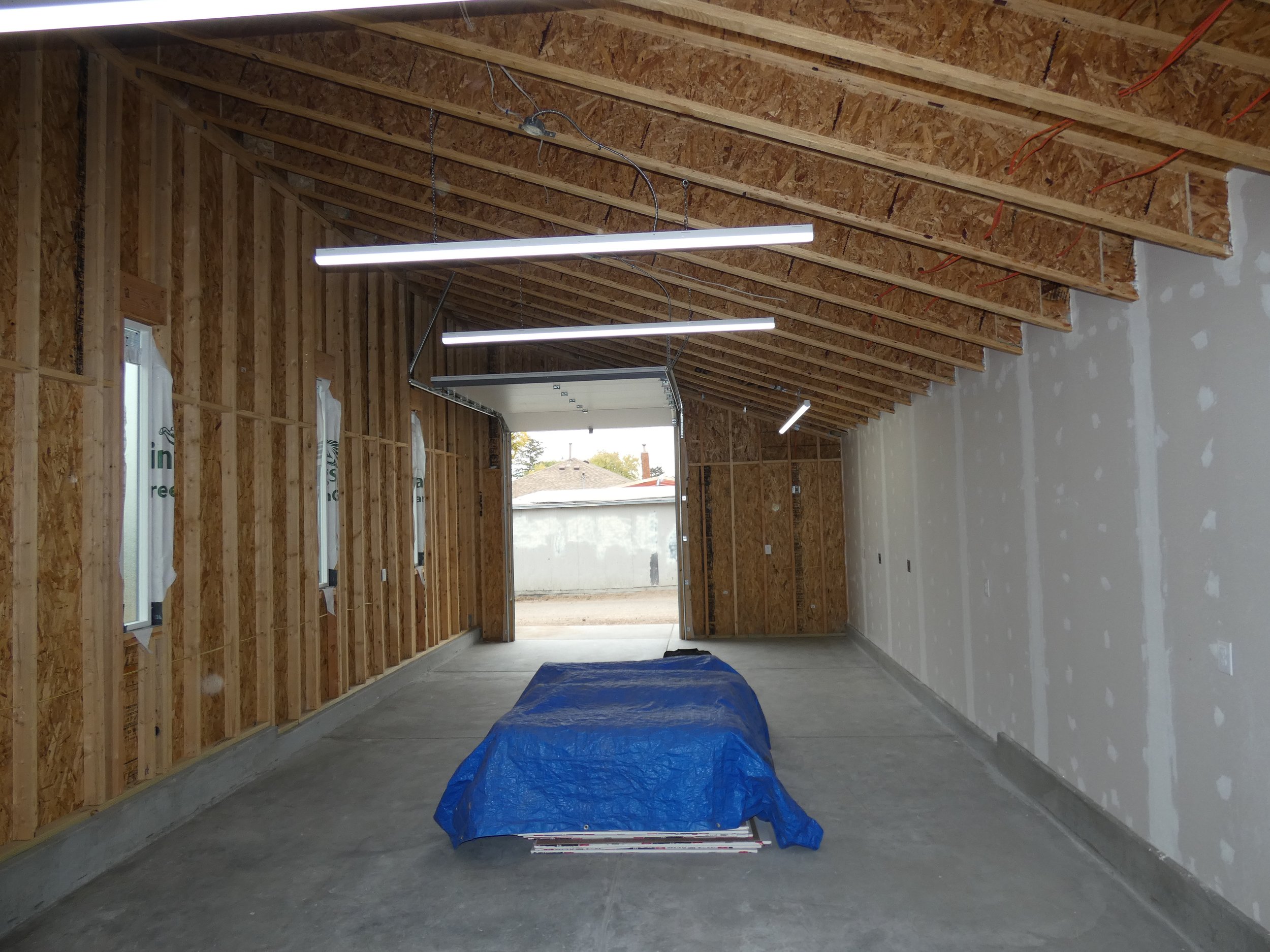Long interior view of a custom detached garage in Denver’s Barnum neighborhood, showing the full depth of the space, high ceilings, and evenly spaced overhead lighting.