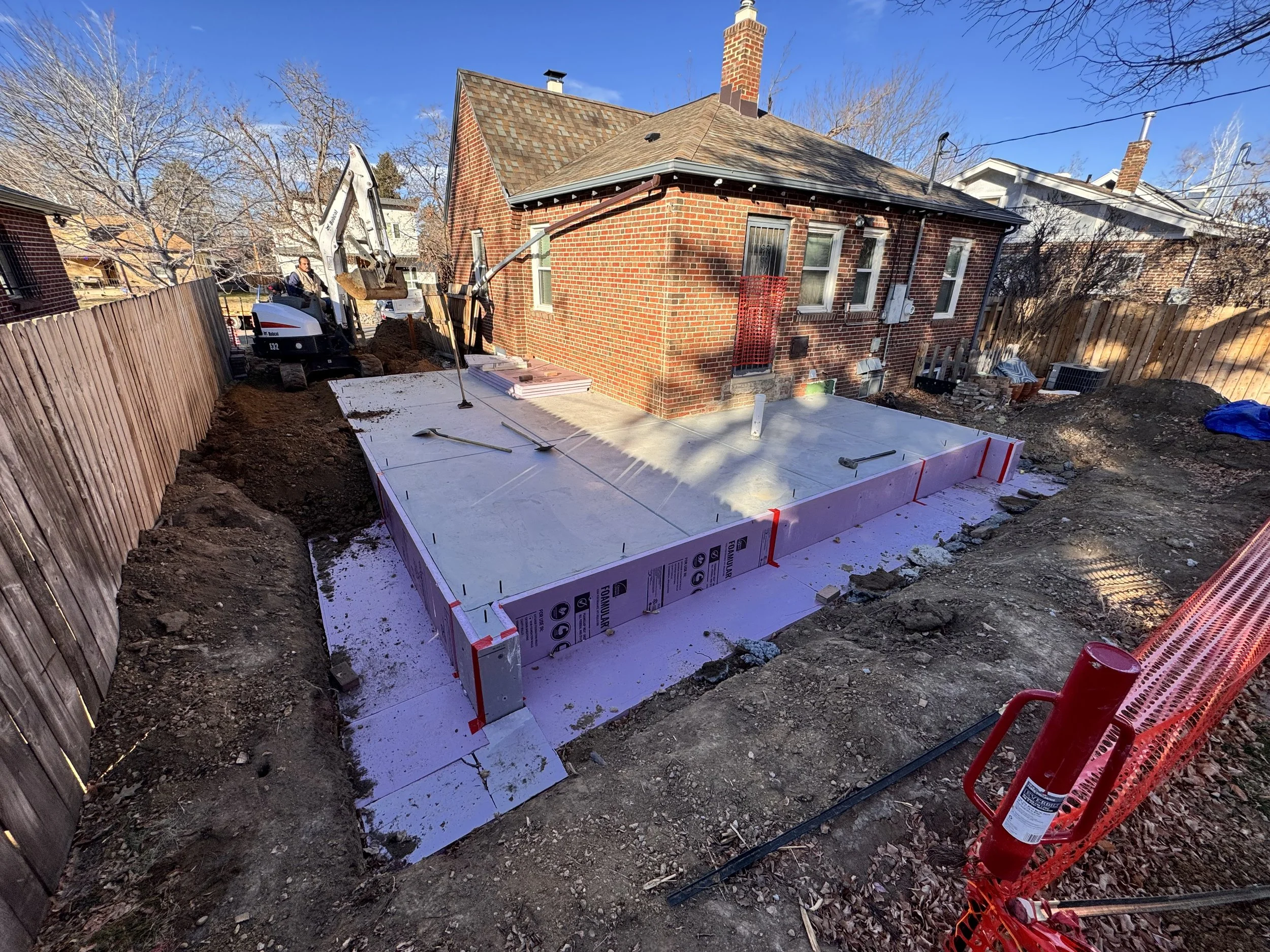 Concrete foundation and slab installation for a Denver home addition, tying a new structure into an existing historic brick residence by Prenvalley Builders.