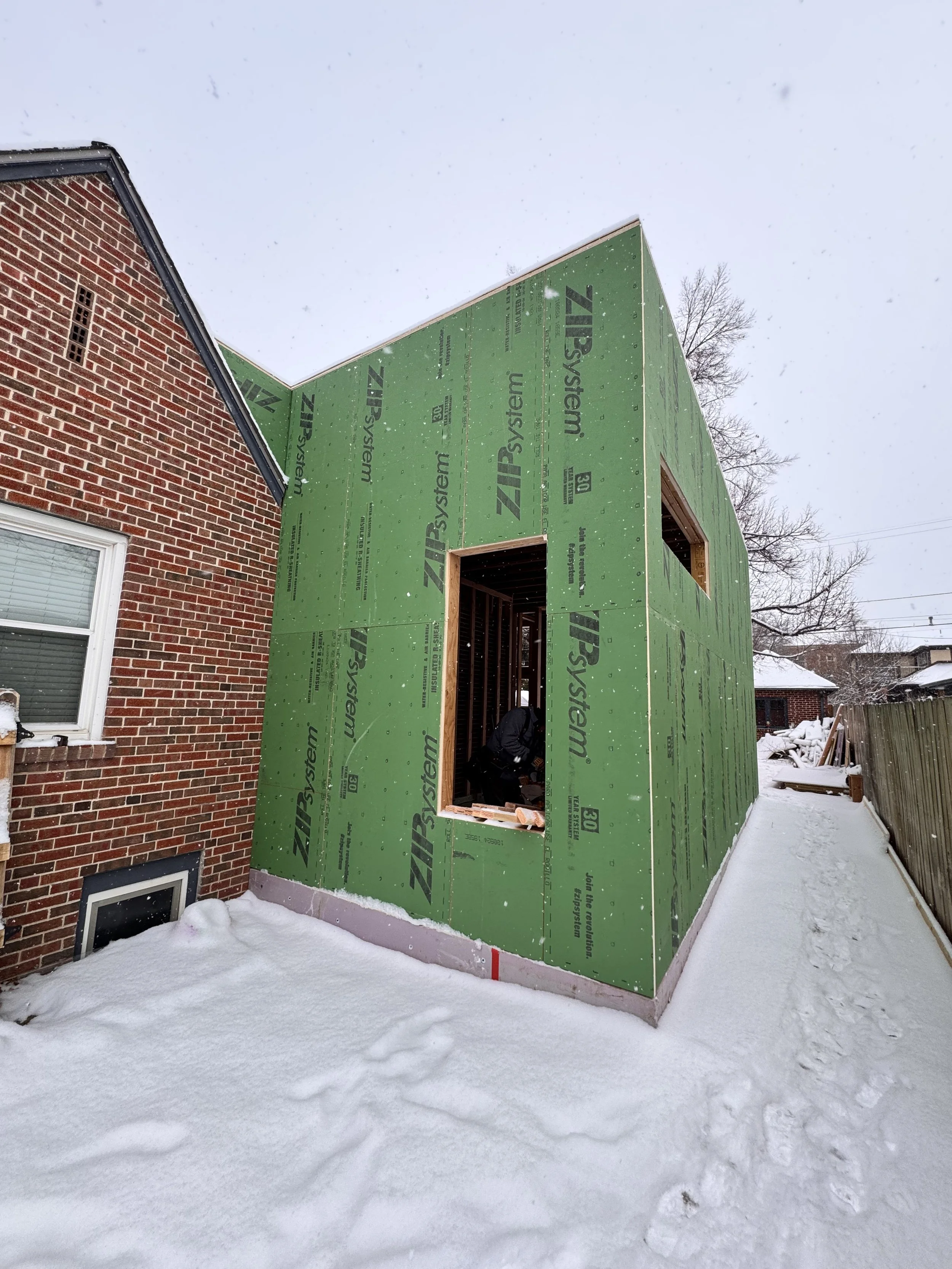 Exterior ZIP System sheathing installed on a Denver home addition, creating a high-performance weather barrier tied into an existing historic brick home by Prenvalley Builders.
