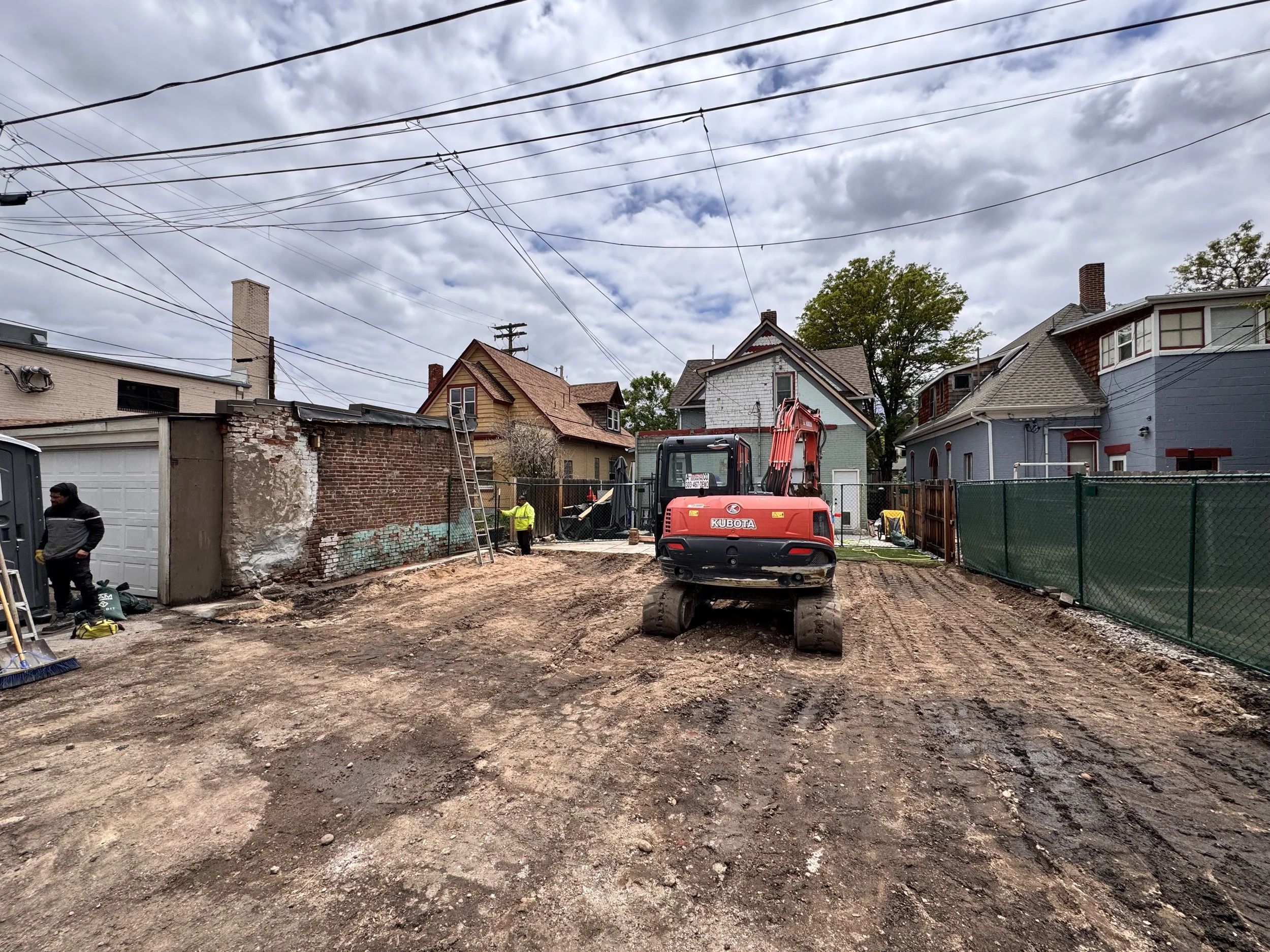 Accessory dwelling unit site preparation in Denver showing demolition, grading, and equipment access within a dense urban lot