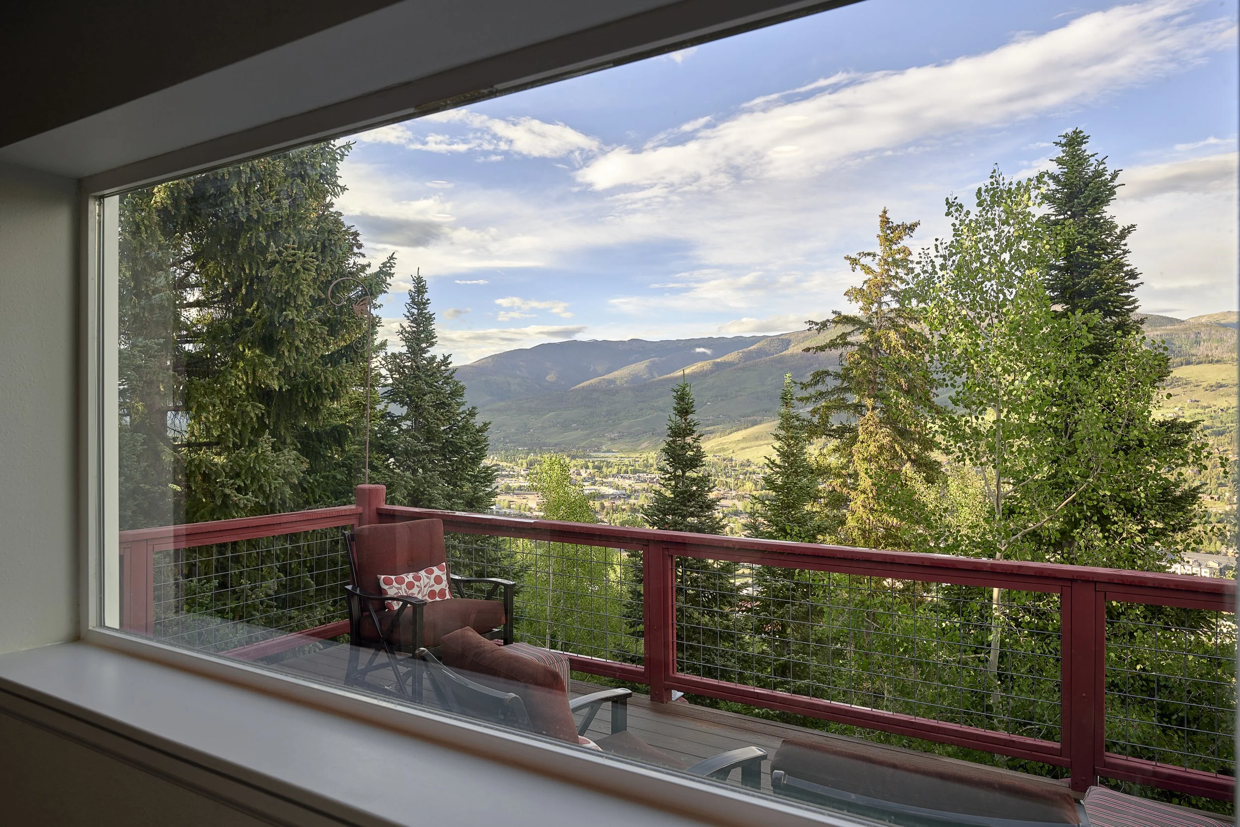 Interior view from an upper-level family space looking out toward a finished balcony and expansive mountain landscape in a Silverthorne pop-top renovation completed by Prenvalley Builders.