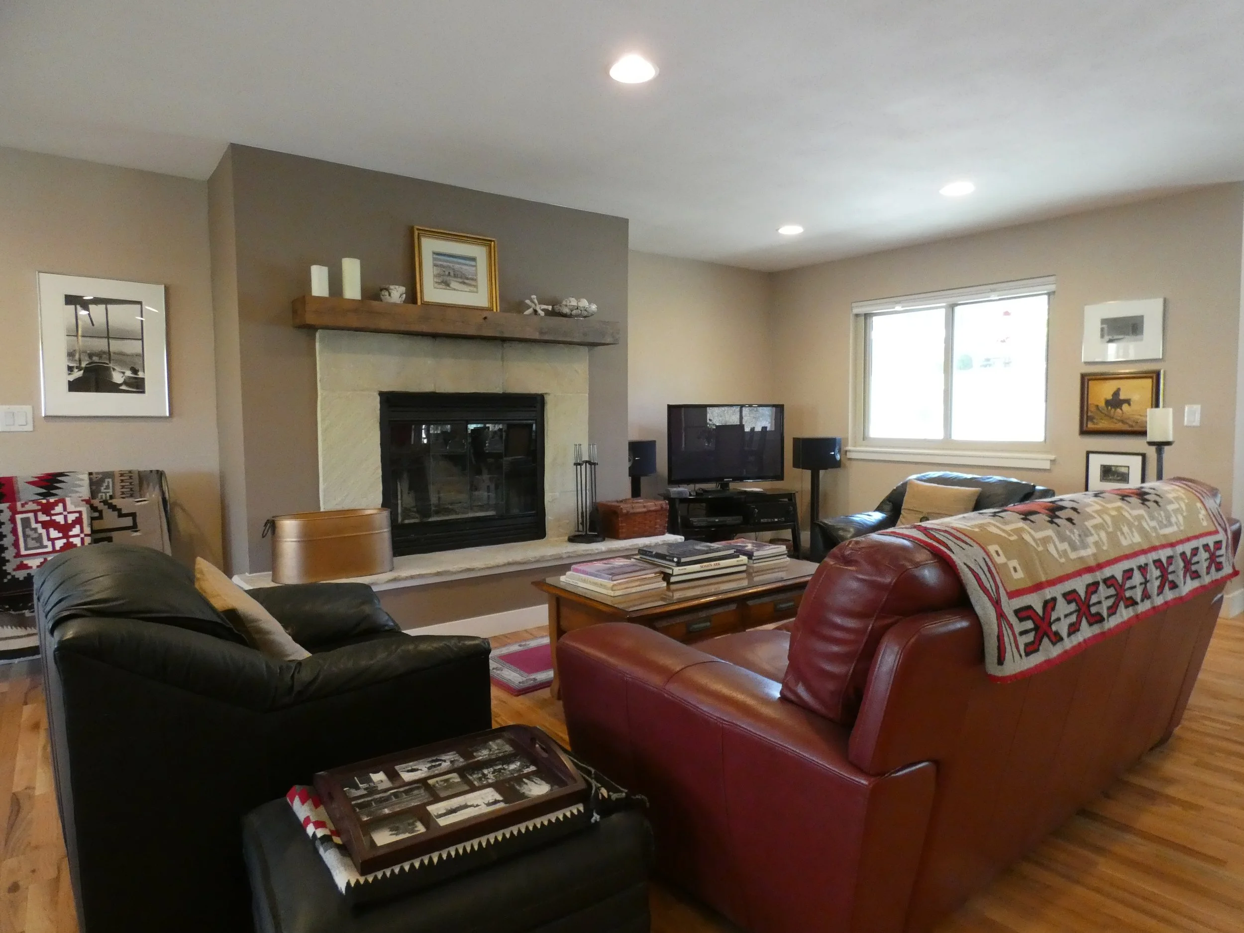 Finished living room with fireplace in a Denver home renovation, featuring hardwood floors, recessed lighting, and a built-in hearth designed and built by Prenvalley Builders.