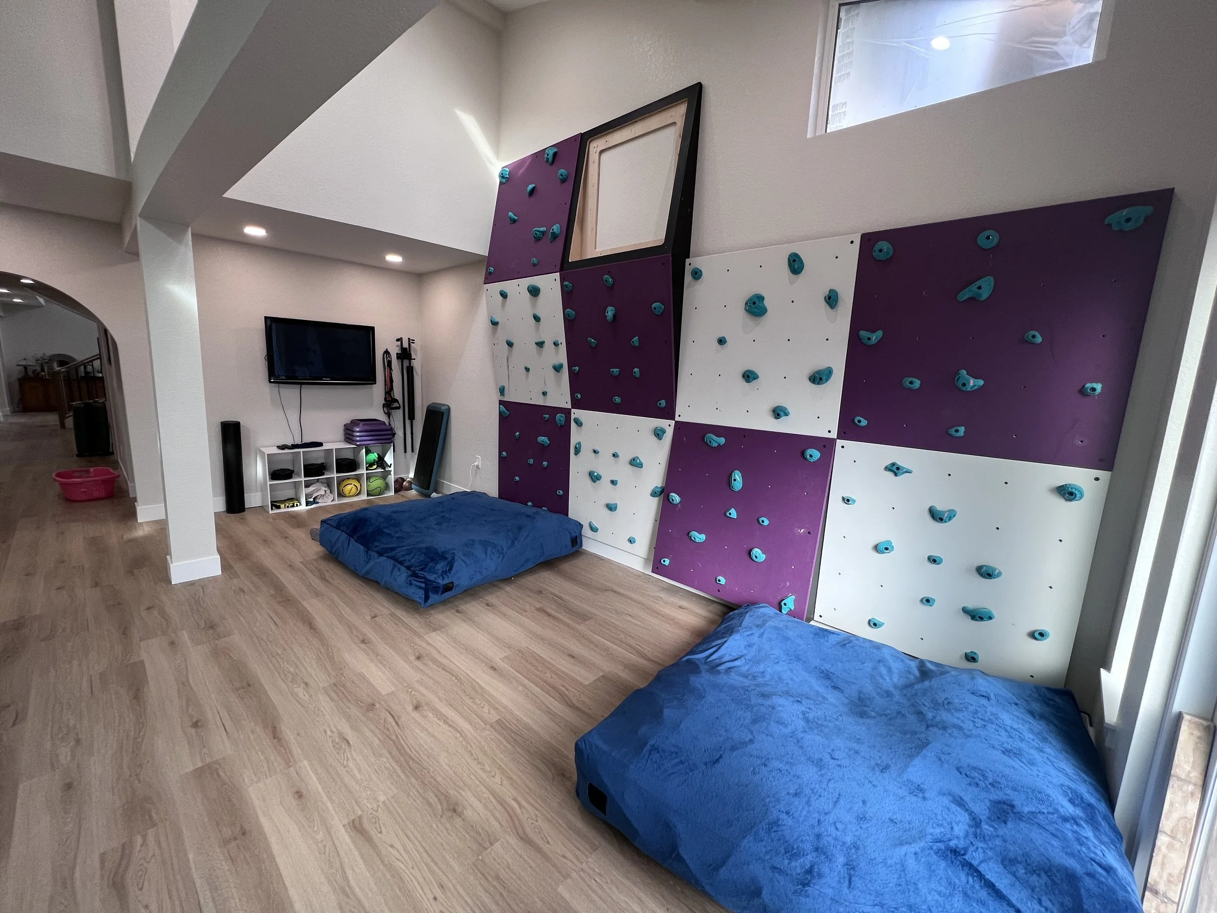 After photo of a lower-level recreation space with a custom climbing wall following a full interior renovation in Golden, Colorado by Prenvalley Builders.