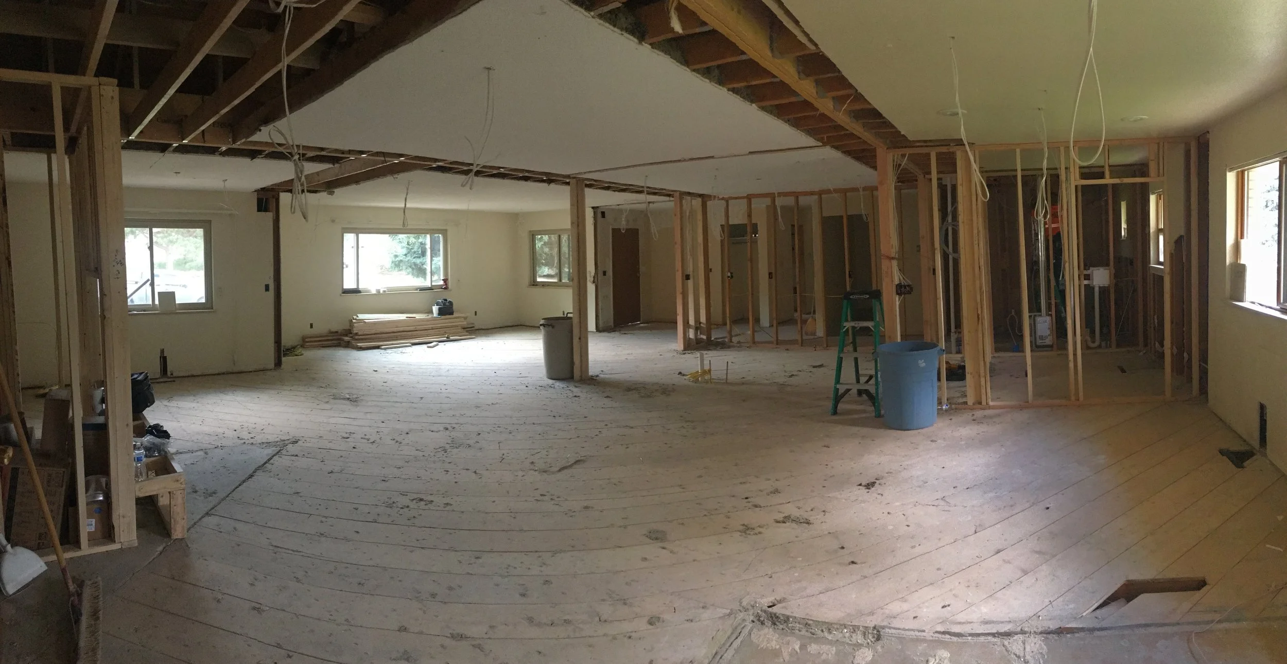 Interior of a Denver home during renovation, showing structural framing, exposed ceiling joists, and an open floor plan created through demolition and reconfiguration by Prenvalley Builders.