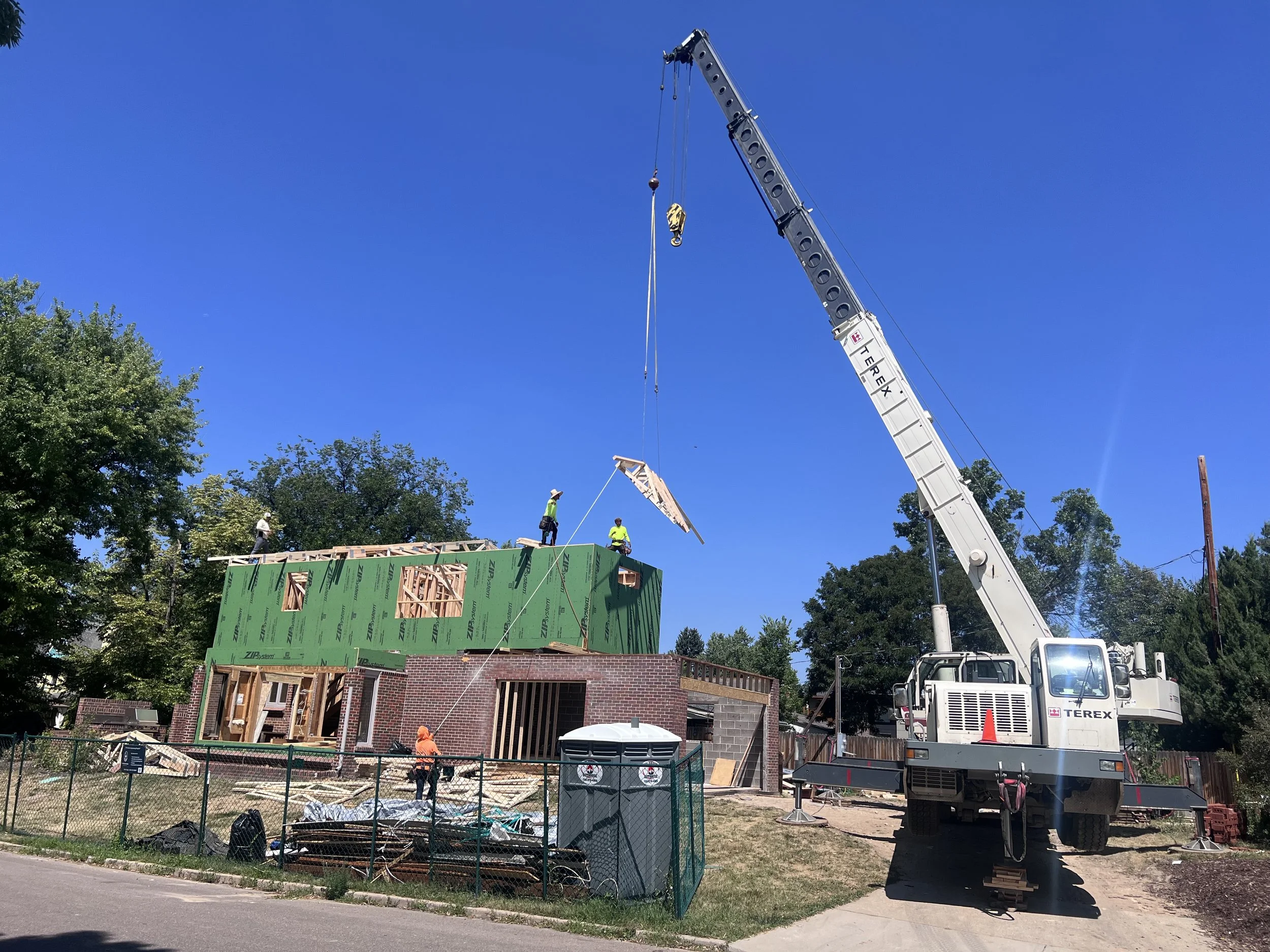 Crane lift installing second-story framing during a Denver pop-top renovation construction phase
