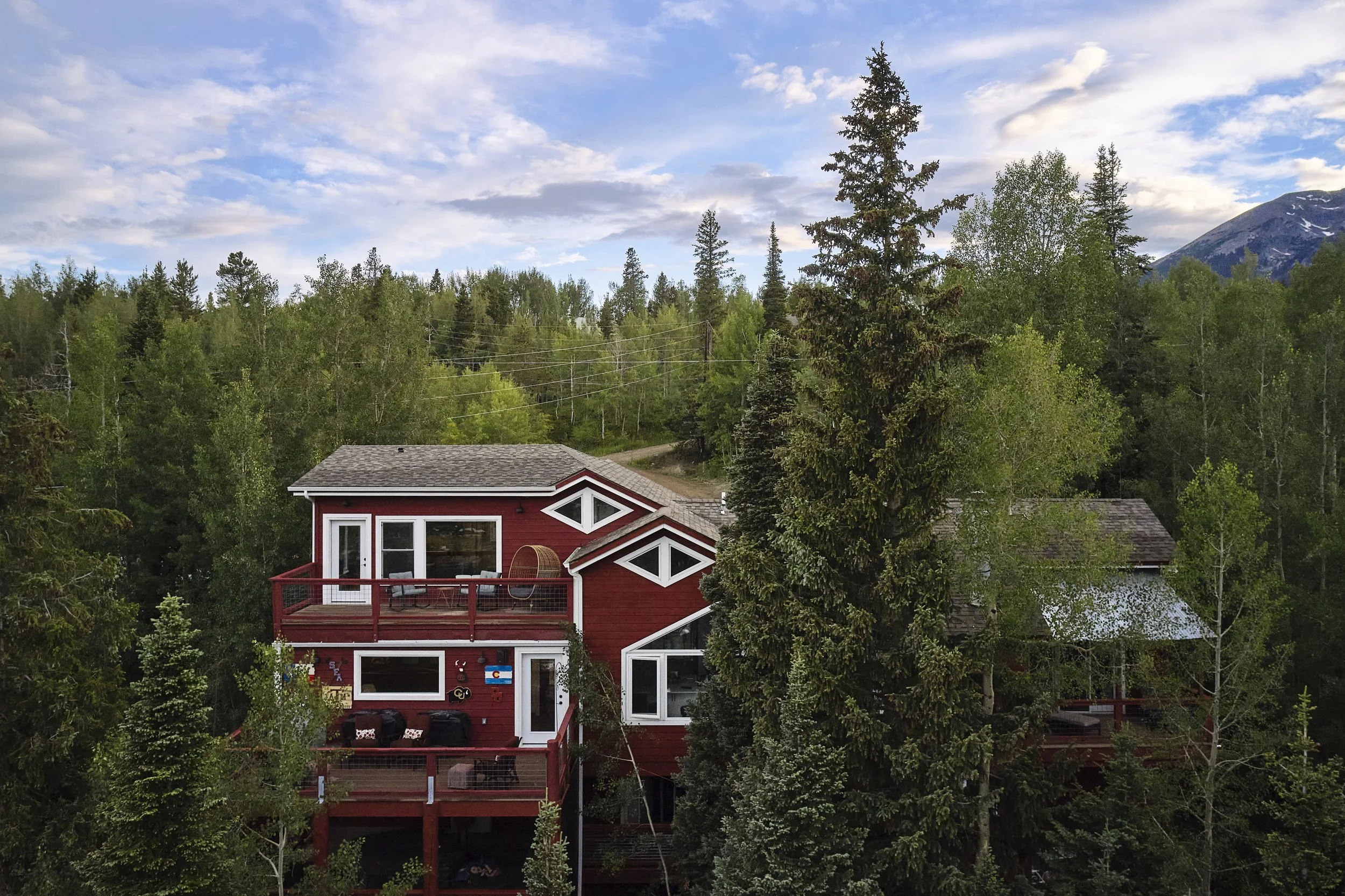 Completed Silverthorne pop-top renovation showing a mountain home with a second-story addition and upper-level balcony, surrounded by trees and designed to capture expansive mountain views by Prenvalley Builders.