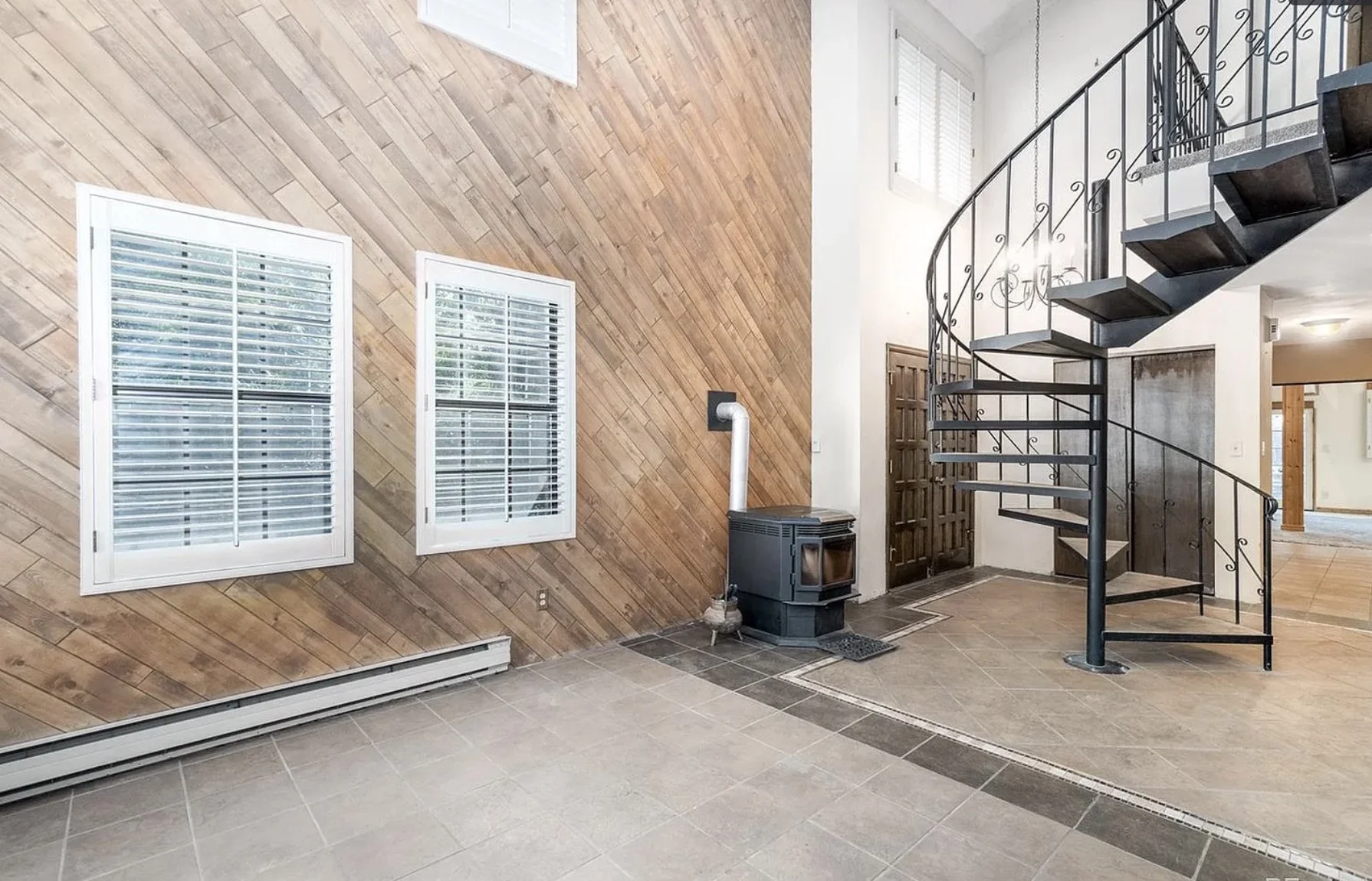 Before photo of an existing interior living area with a spiral staircase prior to a full interior renovation in Golden, Colorado by Prenvalley Builders.