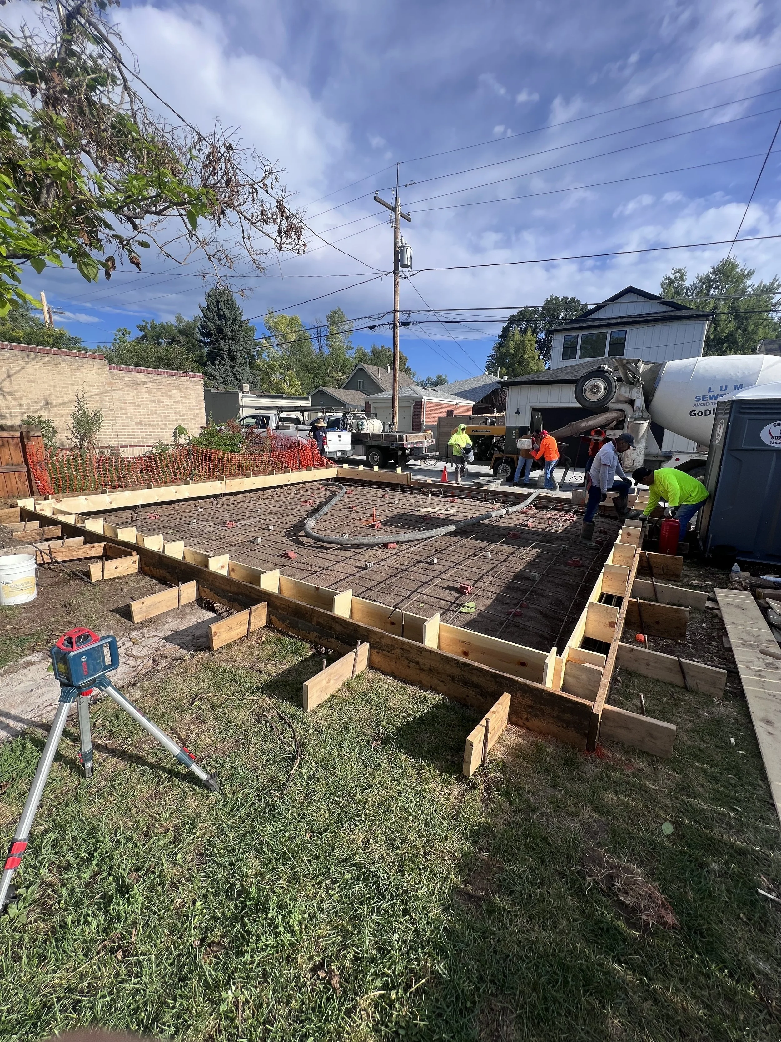 Concrete slab foundation being poured for a new custom detached garage in Denver, Colorado, showing rebar reinforcement, formwork, and site preparation by Prenvalley Builders.
