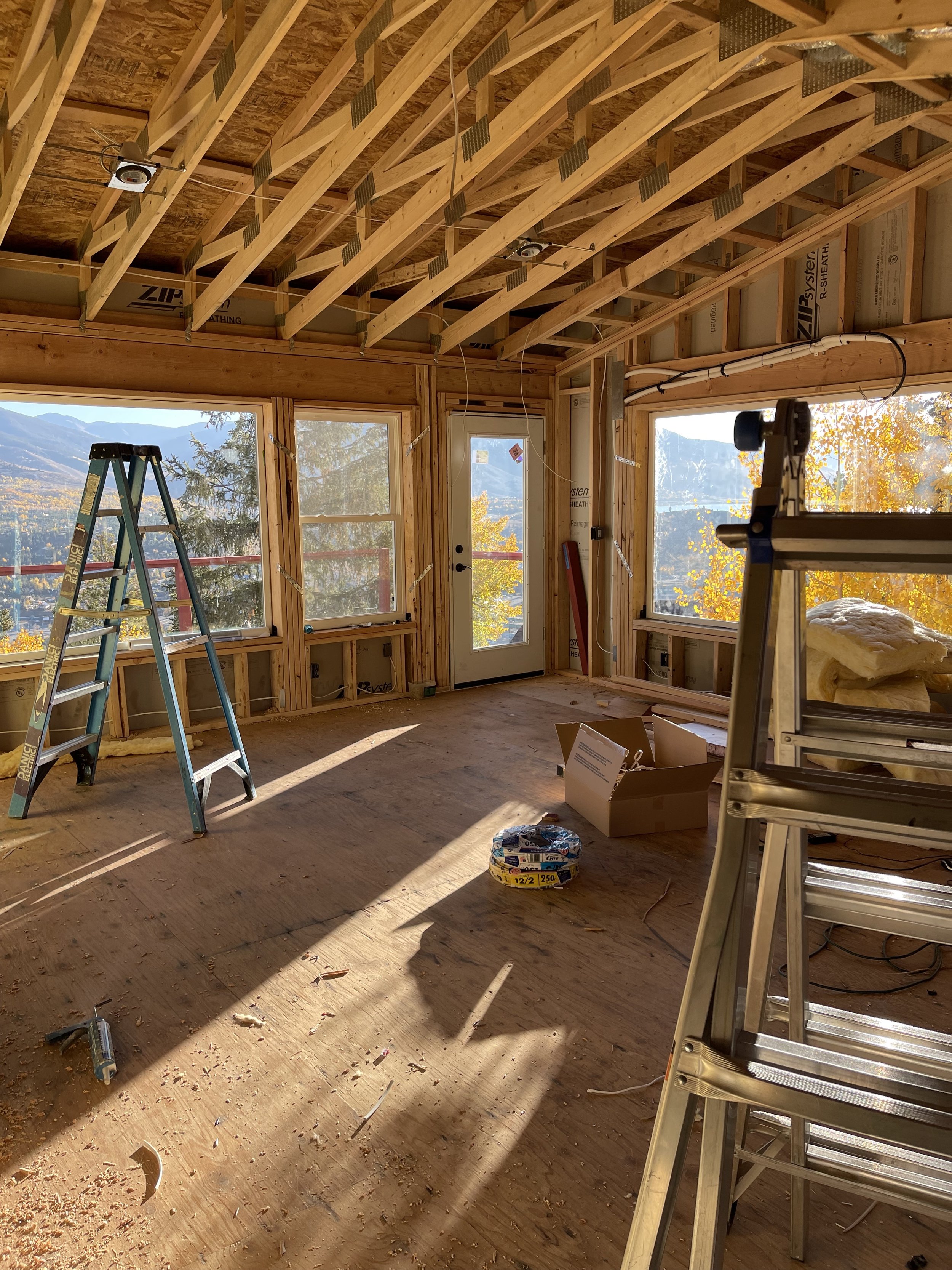 Interior framing of a second-story pop-top renovation in Silverthorne, Colorado, showing new upper-level living space with vaulted ceilings and large windows framing mountain views during construction by Prenvalley Builders.