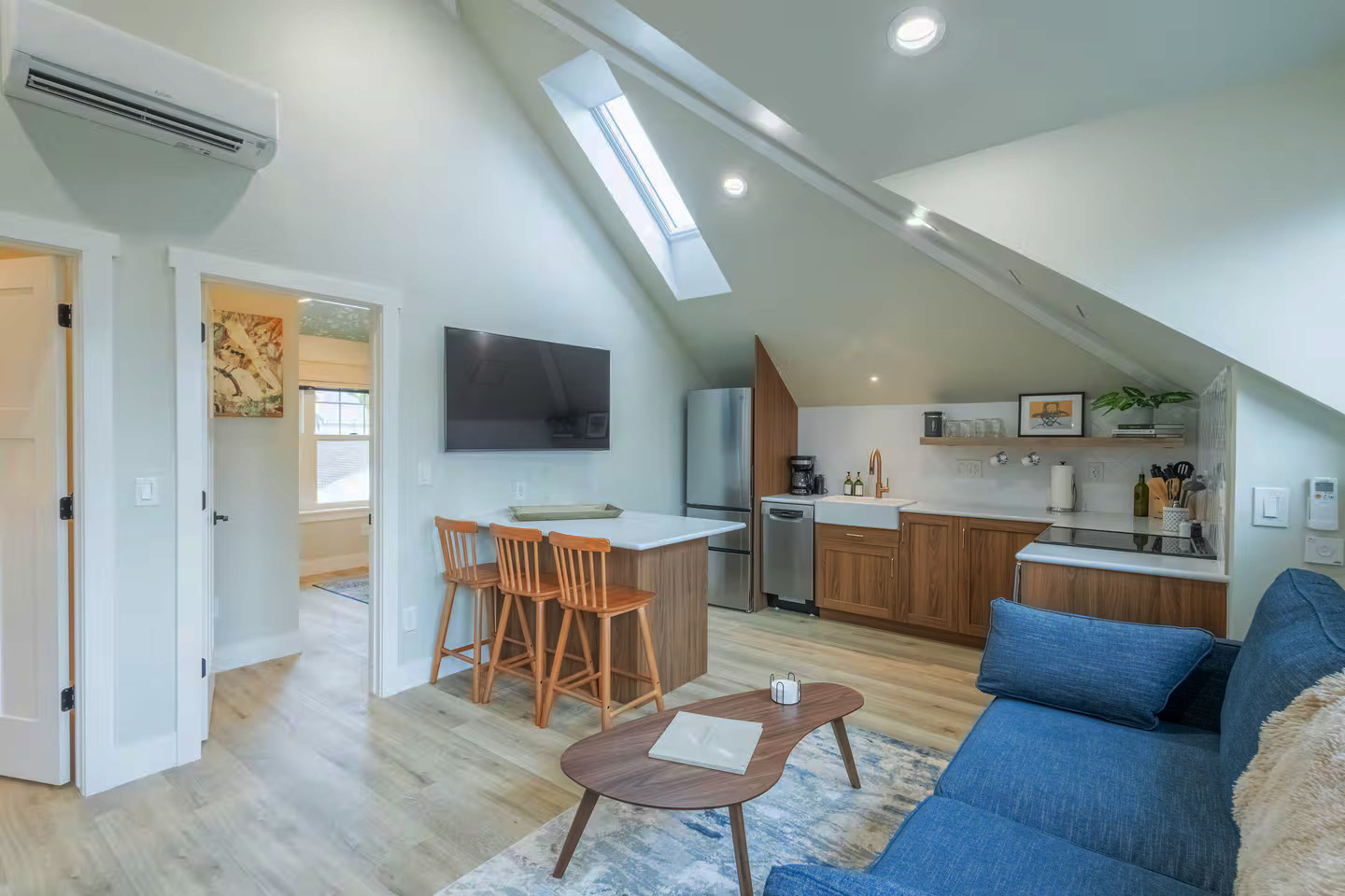 Kitchen interior of a custom Denver ADU featuring vaulted ceilings, a skylight, modern wood cabinetry, island seating, and energy-efficient appliances designed by Prenvalley Builders.