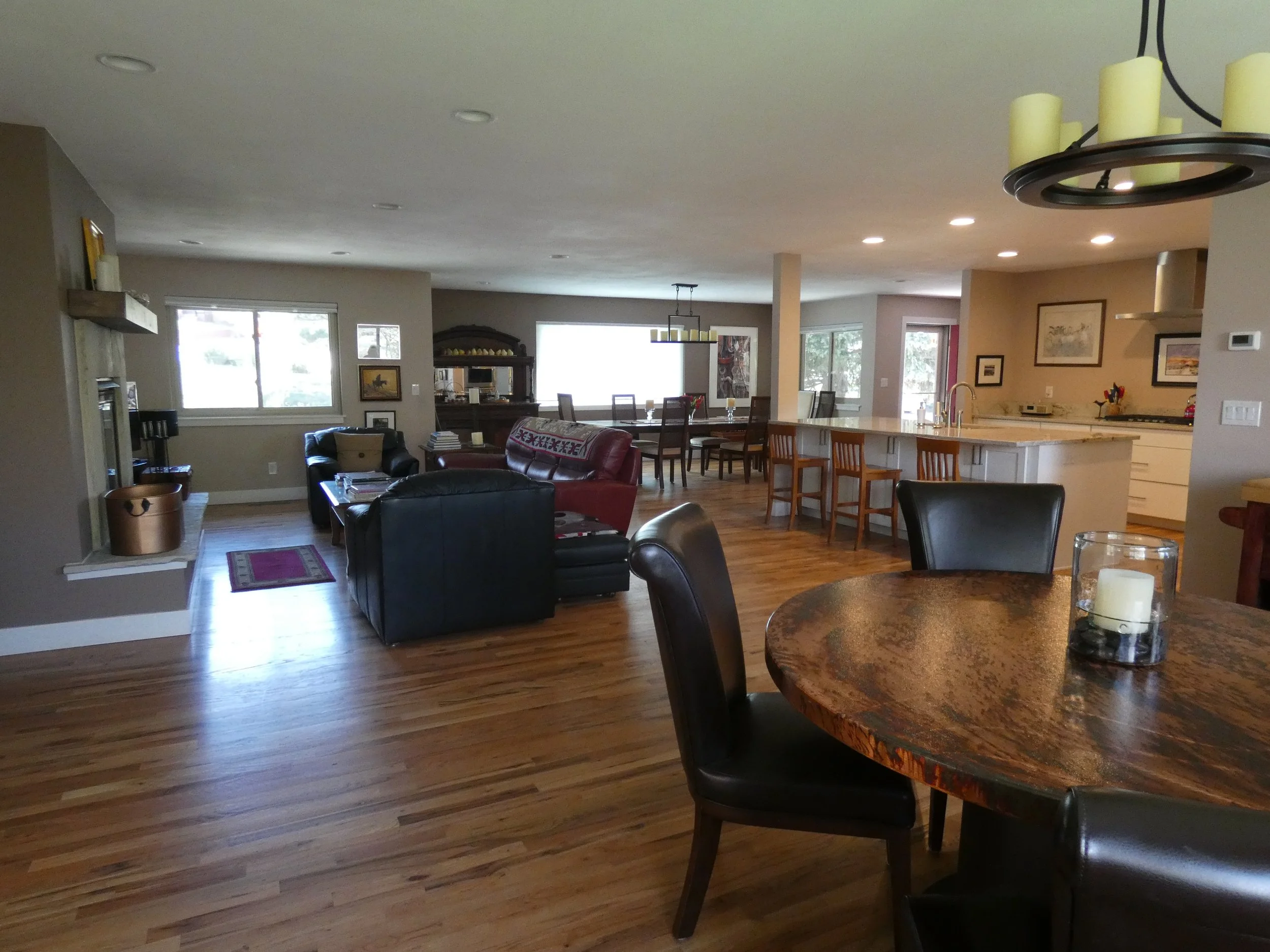 Completed open-concept living, dining, and kitchen space in a Denver home renovation, featuring updated hardwood floors, recessed lighting, and a seamless layout designed and built by Prenvalley Builders.