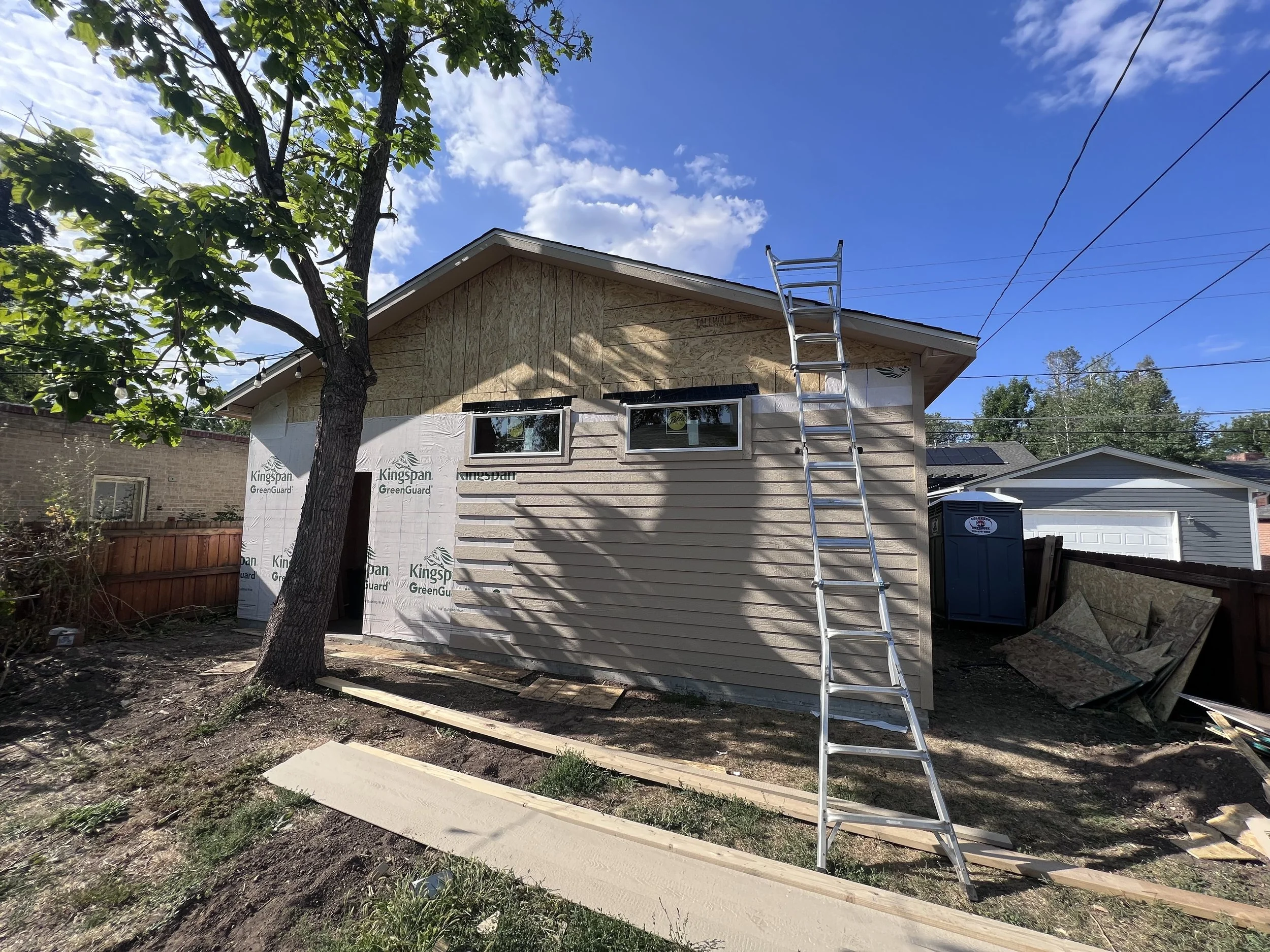 Exterior view of a custom detached garage under construction in Denver, Colorado, showing completed framing, roof structure, window installation, and siding in progress by Prenvalley Builders.