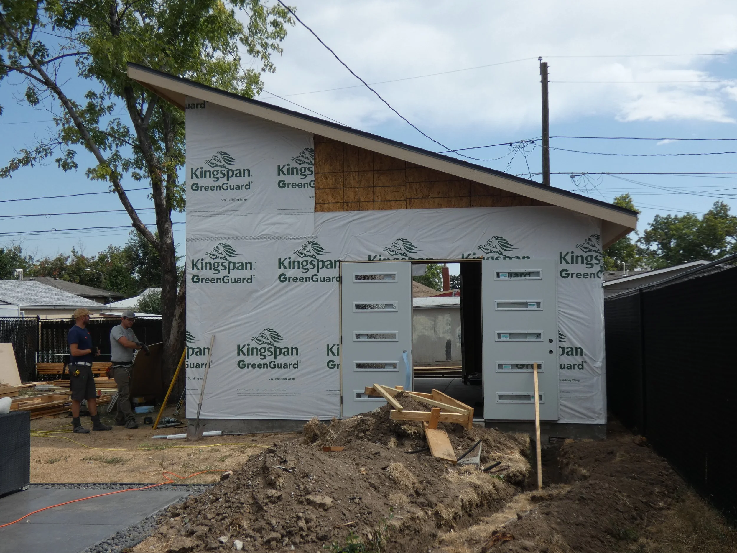 Front entry of a custom detached garage in Denver’s Barnum neighborhood, featuring a single-slope roof and tall doors designed for large vehicle access. Prenvalley Builders construction crew working on the build phase of this custom garage.