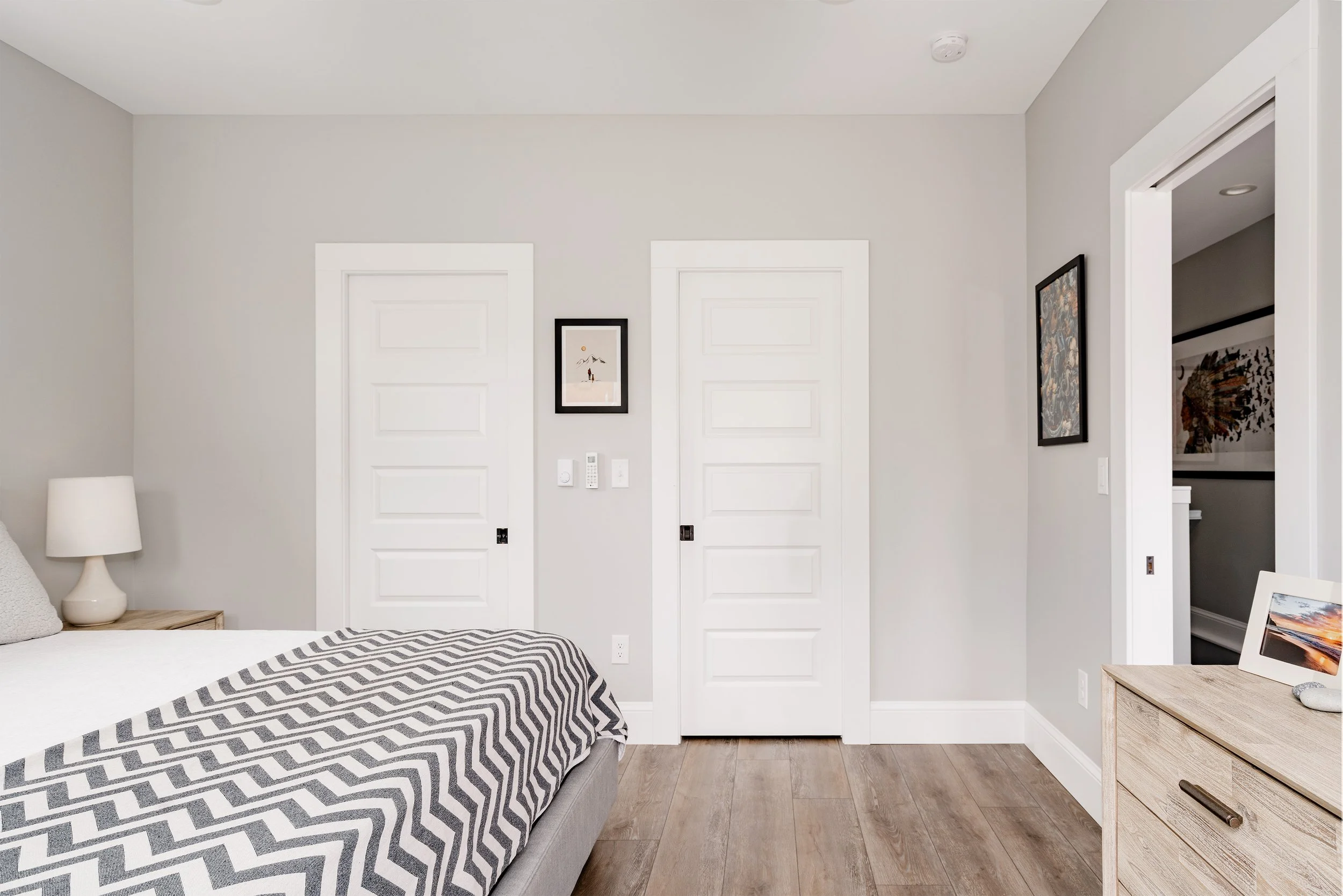 Primary bedroom inside a Denver home addition featuring clean modern finishes, wood flooring, and direct access to storage and closet spaces built by Prenvalley Builders.