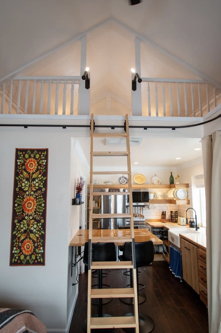 Loft interior inside a detached accessory dwelling unit in Denver, Colorado, built by Prenvalley Builders, featuring ladder access, open railing, and vaulted ceiling above the main living space.