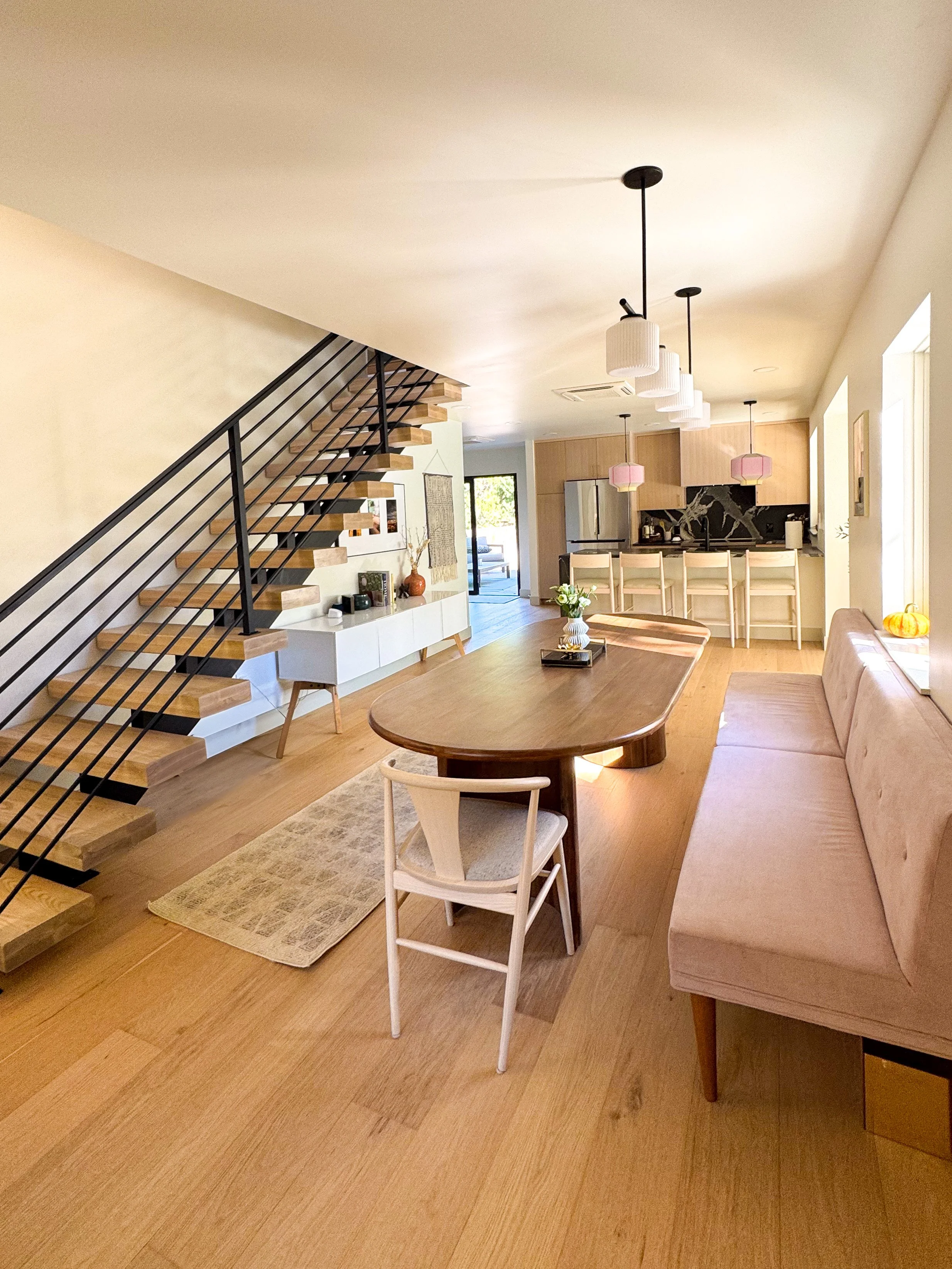 Open living and dining space in a Denver pop-top renovation featuring a custom staircase and seamless connection to the kitchen