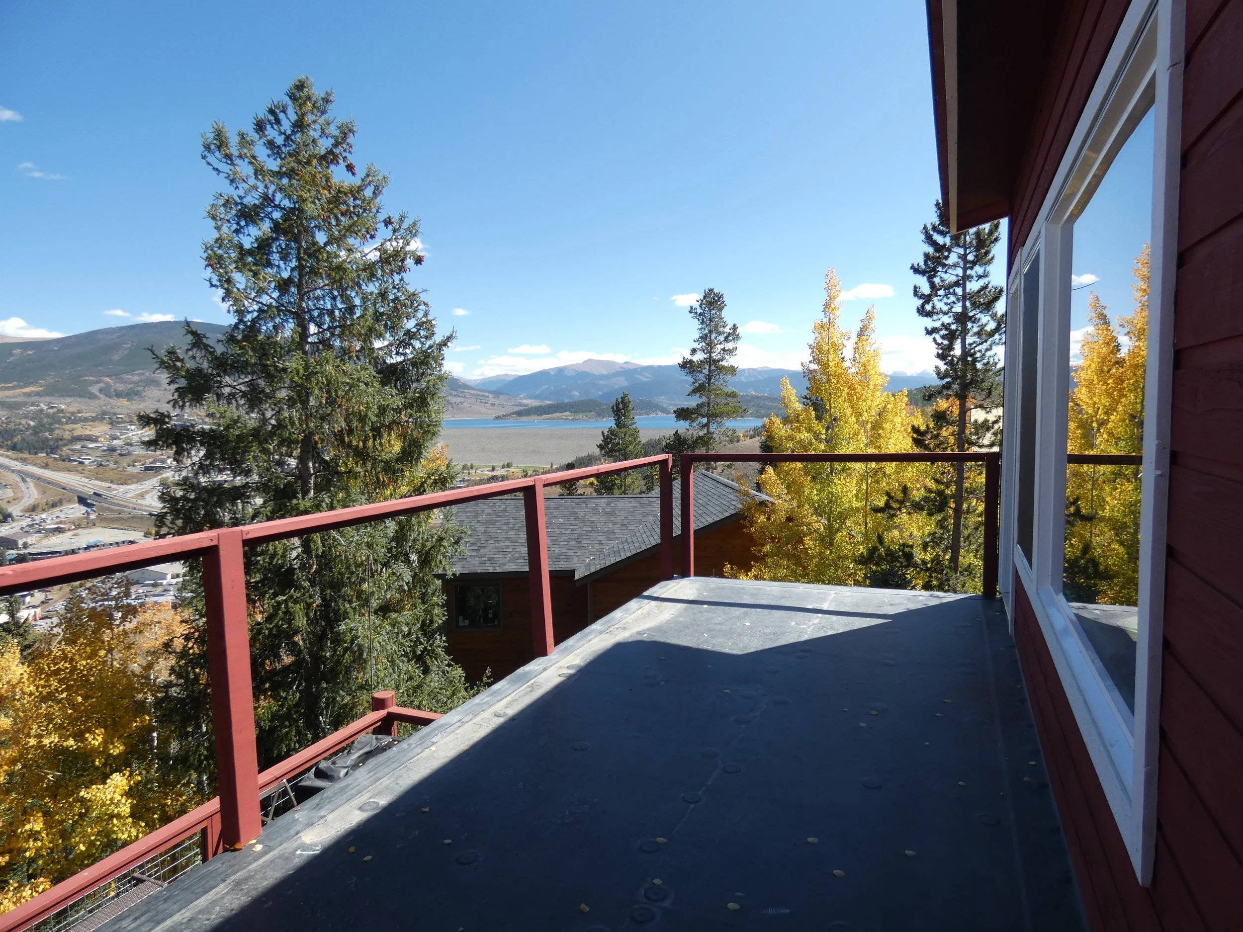 Upper-level balcony under construction in a Silverthorne pop-top renovation, showing unfinished decking and expansive mountain and Lake Dillon views from a second-story addition by Prenvalley Builders.