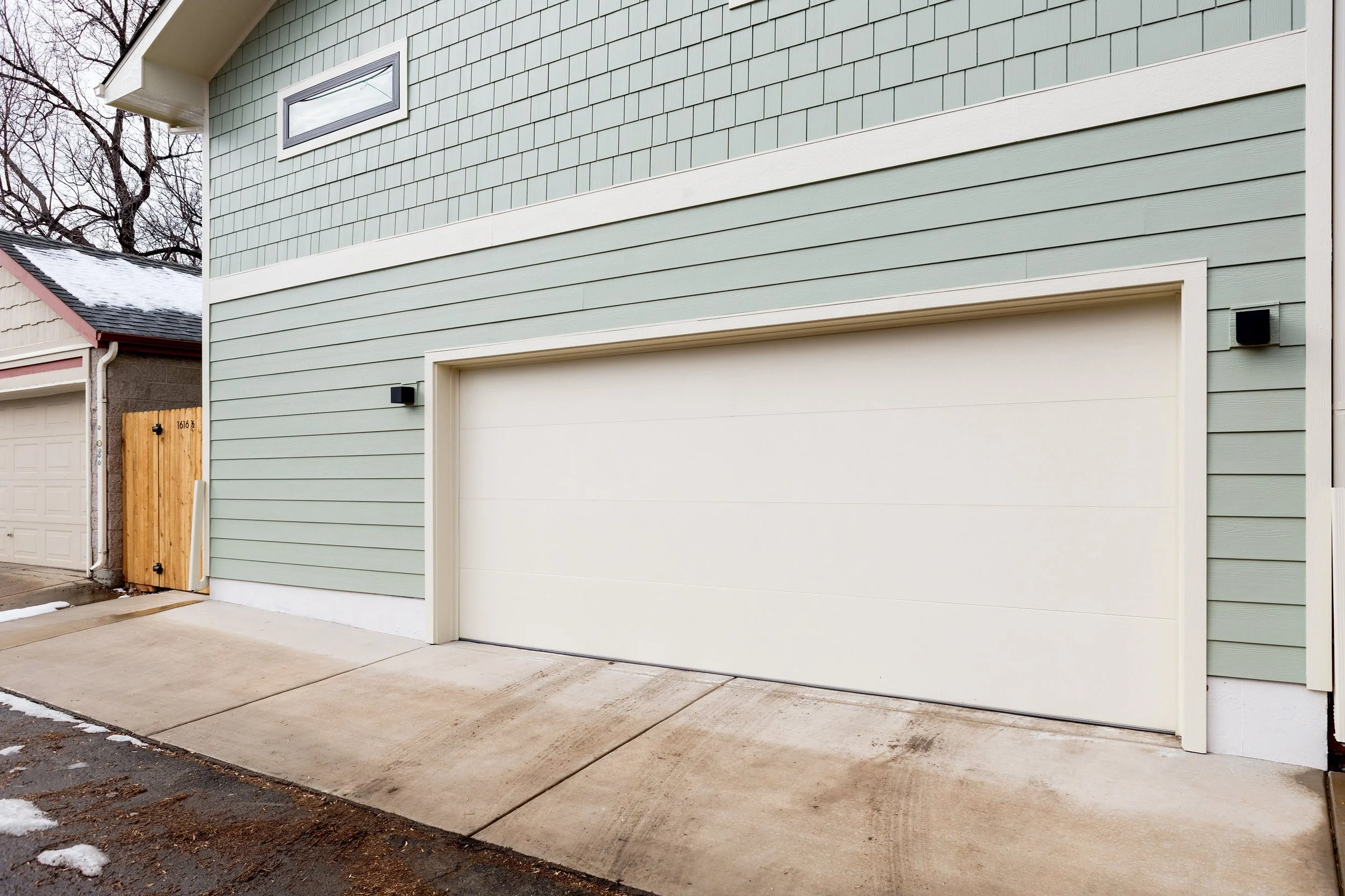 Detached Denver ADU garage exterior with horizontal lap siding, a modern garage door, and clean concrete driveway.